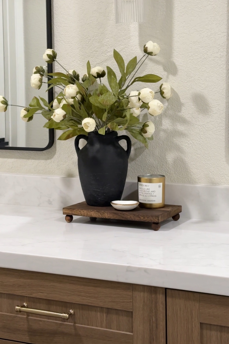 Bathroom counter styling 🤍

These peonies were a best seller last year and I love the way they look in our primary bathroom! Styled on a wooden riser paired with a candle and jewelry dish. 
This monogrammed jewelry dish was an engagement gift from a friend! 🫶🏻
•••
Bathroom accessories, bathroom styling, bathroom counter decor, counter decor, primary bathroom, master bathroom, master bath, wood risen, wooden riser, wood tray, footer tray, black vase, rustic vase, faux florals, faux peonies, fake flowers, fluted scone, champagne bronze, drawer pulls, champagne bronze trim, champagne bronze hardware 

#LTKHome #LTKFindsUnder50 #LTKStyleTip