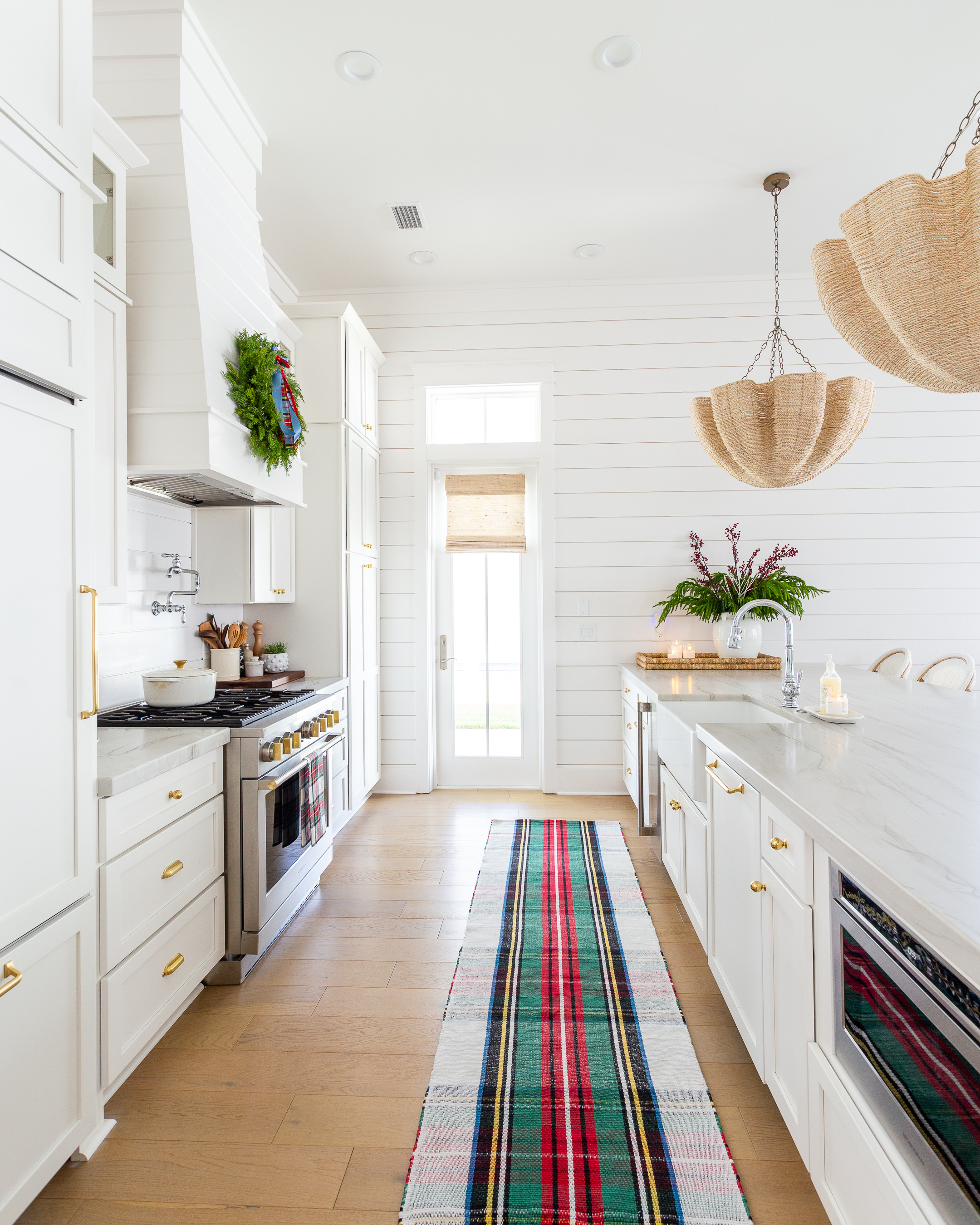 Our coastal kitchen with white cabinets and white oak floors, decorated for Christmas with a tartan plaid rug, real-touch wreath, Christmas bows, flameless candles pillars, scalloped woven chandeliers, and Christmas hand soap. #ltkhome #ltkholiday #ltkseasonal #ltkfindsunder50 #ltkfindsunder100 #ltkstyletip #ltksalealert 

 #LTKHoliday #LTKHome #LTKSaleAlert
