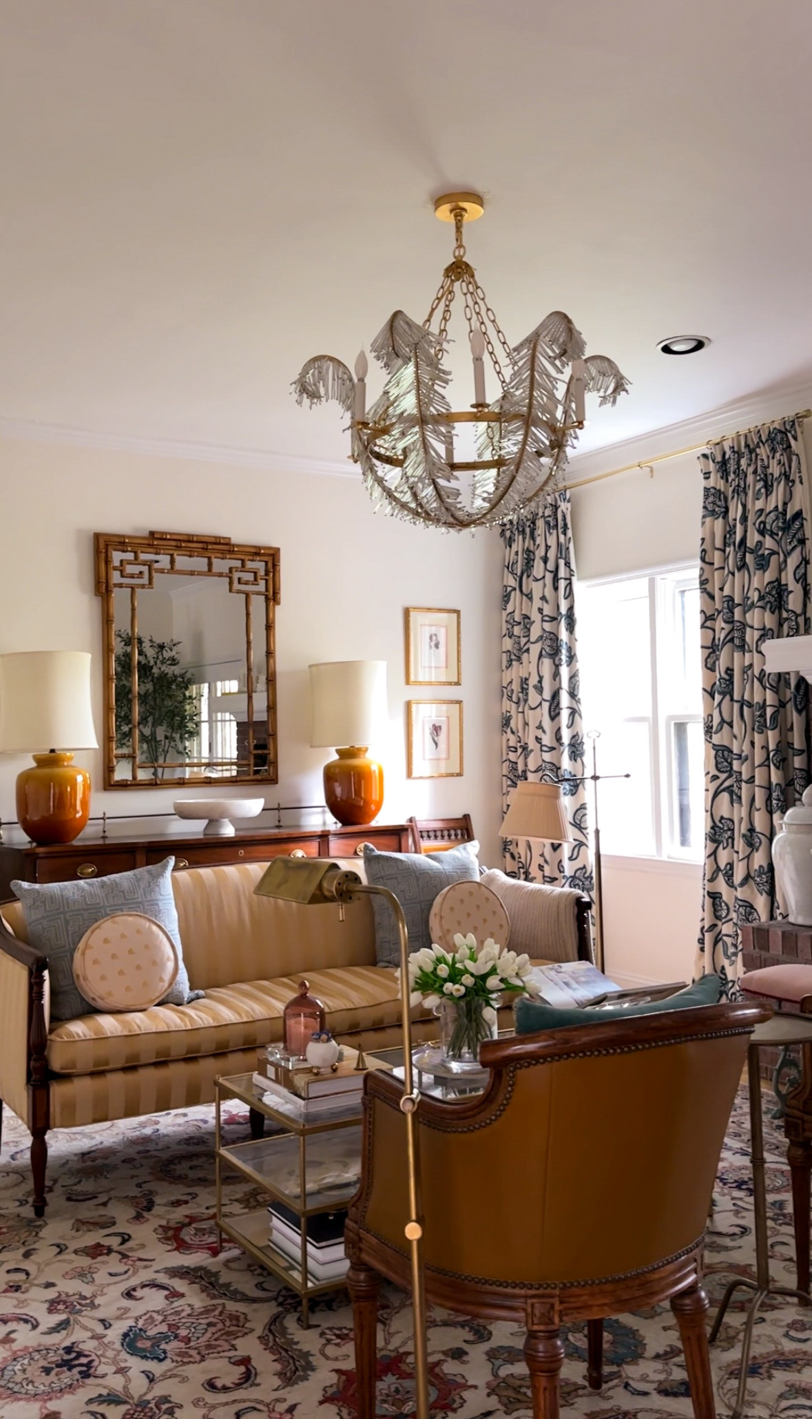 Grandmillennial style living room with layered traditional pieces, a fringe chandelier, floral drapes, and a statement leather chair.
Perfect for anyone styling a collected, neo-traditional space with vintage charm and elevated details. 

 #LTKHome
