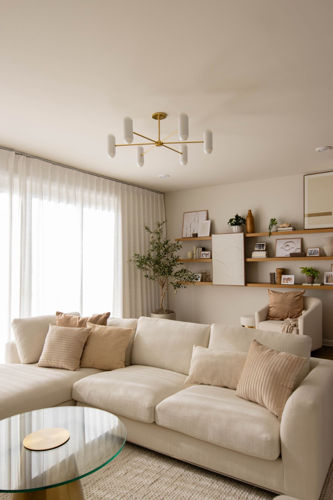 Light and airy organic modern living room with Mitizi chandeliers , faux olive tree, neutral decor, linen curtains and oak shelves 