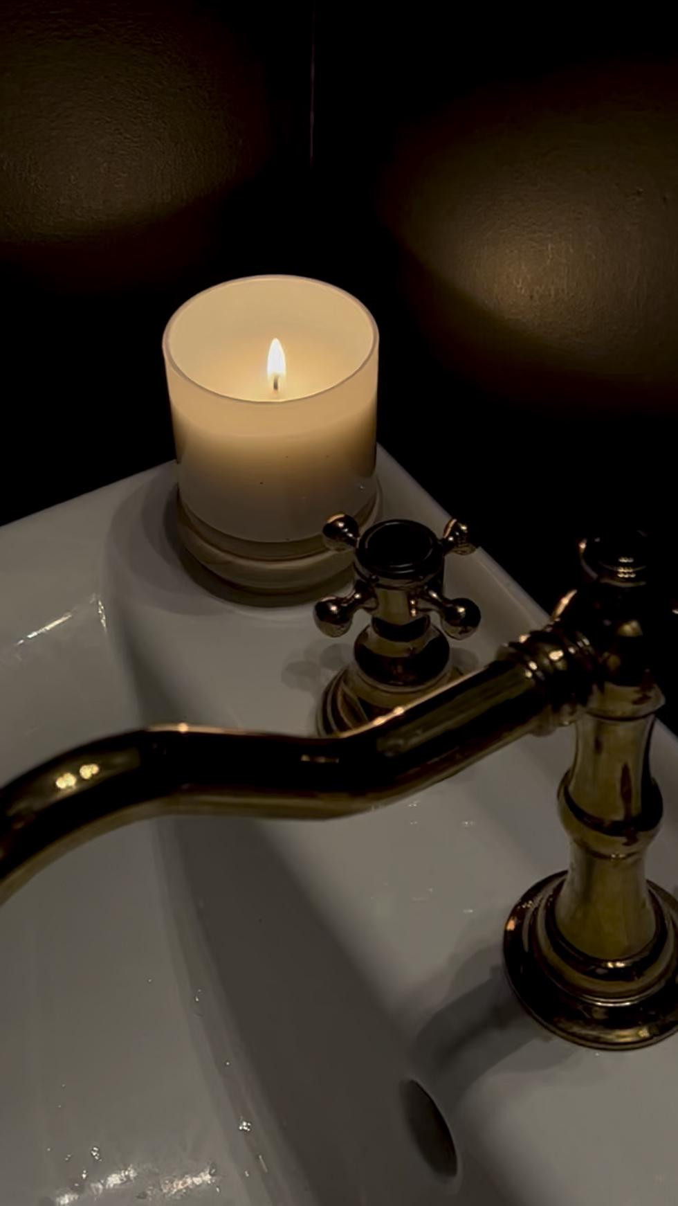 A flickering candle casts a soft glow over the white Kohler sink, highlighting the warm shine of the polished brass faucet. In this dramatic powder room, the mix of brass and black feels both cozy and elevated — a little moment of quiet luxury in everyday life. ✨

#LTKSeasonal #LTKSaleAlert #LTKHome