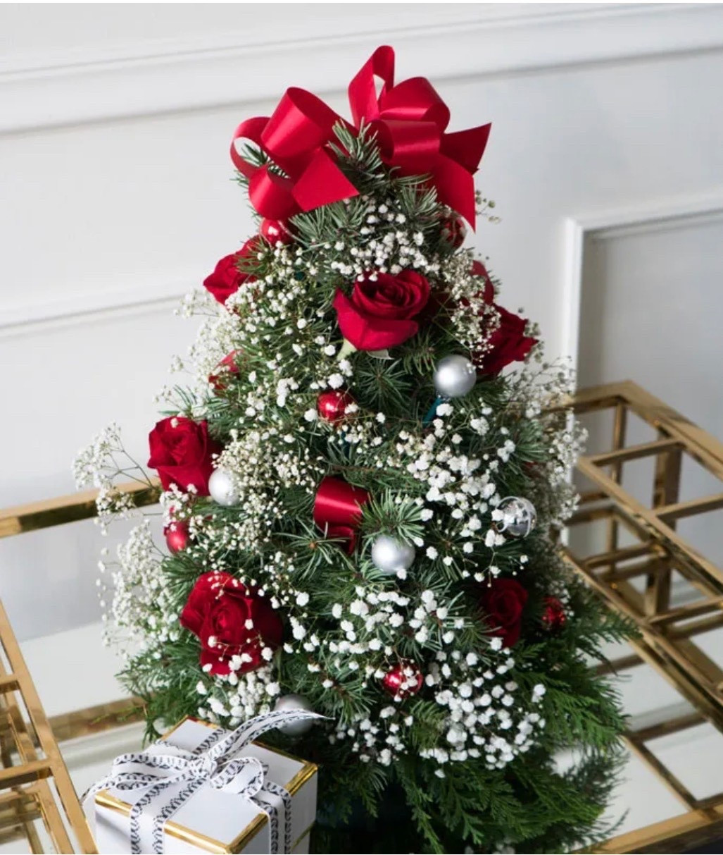 ✨ Please note that these are fresh flowers. ✨

Celebrate the season with this festive floral arrangement designed in the shape of a Christmas tree. Featuring vibrant red roses nestled among delicate white baby's breath and lush seasonal greens, this piece is accented with mini silver ornaments and decorative red ribbon for a cheerful holiday touch. Perfect as a centerpiece or a thoughtful gift, it brings warmth and elegance to any holiday setting. This DELUXE floral arrangement is ON SALE and is under $70.

Includes:
• Red Roses
• White Baby's Breath
• Seasonal Greenery
• Miniature Silver Ornaments
• Decorative Red Ribbon
• Personalized Card Message

Keywords: Hostess gift, floral bouquet, holiday gift, holiday present, gifts for her, gifts for them

#LTKSeasonal #LTKHoliday #LTKSaleAlert