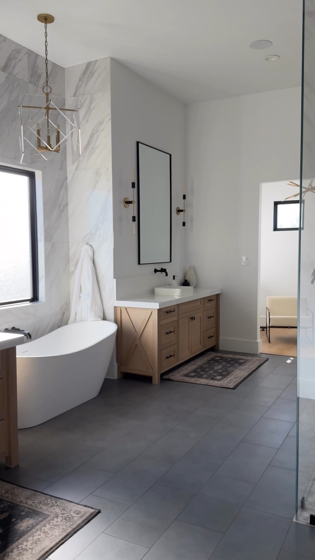 It’s possible to have the bathroom of your dreams without spending a fortune. Here’s how we made it happen: 
details.

We chose affordable floor tile and that savings allowed us to splurge on Schluter Ditra heated floors. Rather than solid slabs, the large format porcelain tile on surrounds were a steal at $2.69/sqft (at the time of purchase) which helped us invest in a sleek American Standard 72” Sheba Resin Bathtub. Instead of custom mirrors, we went with oversized prefabricated mirrors with modern black metal frames for a fraction of the price. With the savings, we splurged on a 10’ Starphire Ultra Clear glass shower enclosure. We did budget-friendly sconces and invested in a statement chandelier for over the tub. Lastly, rather than a pricier natural stone, we chose clean, simple white zen quartz countertops. 

By strategically saving on key elements, we were able to splurge in other area to achieve the perfect balance for our dream master bathroom. 

#homeinspo #homeinspiration #homeblogger #homedesign #bathroominspo #bathroominspiration #bathroomrenovation 

#LTKHome #LTKFindsUnder100 #LTKSaleAlert