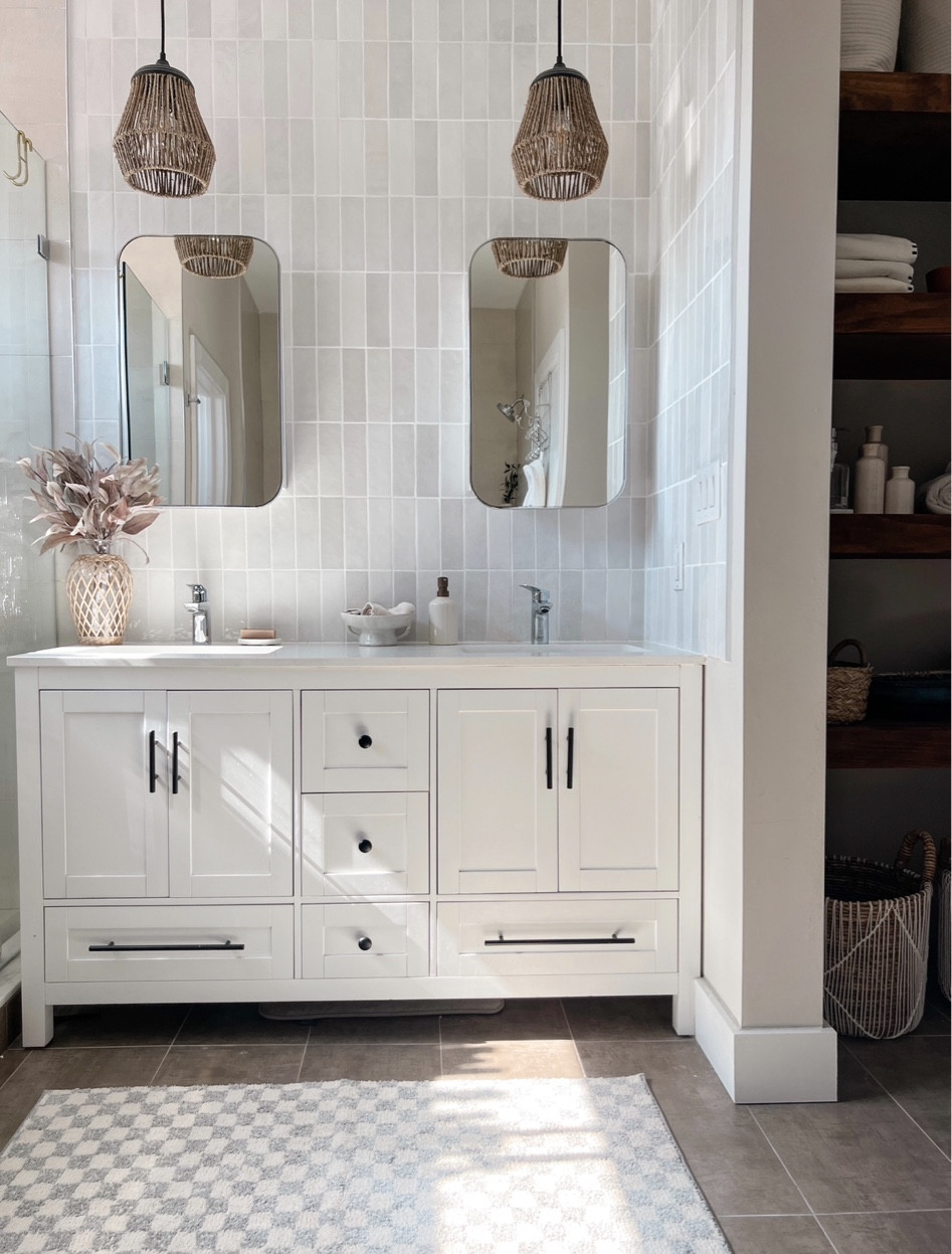 HOW TO (EASILY) UPGRADE YOUR BUILDER GRADE BATHROOM:

	1	Add custom shelving. We DIYed floating shelves into this weird empty space our builders left for us. 
	2	Add a backspalsh. We chose to take the tiles up to the ceiling for an elevated look. We chose to DIY this project too and tiling was easier than we anticipated (with some guidance from a neighbor who had experience!) 
	3	Switch our mirrors, hardware, and lighting. This is the easiet and most affordable way to upgrade your bathroom without spending a ton of money or having to learn any new skills!
	4	Add decor such as rugs, pretty hand soap dispensers, and an upgraded way to hold your hand towels like this ceramic dish I found. We didn’t want to have to drill into our pretty new tile to install a hand towel holder so I love this alternate method! 


#LTKhome #LTKFind