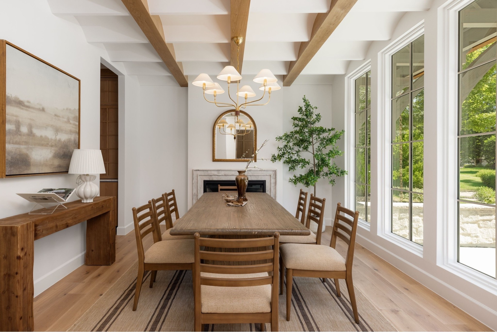 Wood dining table, ladder-back chairs, and a striped rug anchored by a statement gold mirror and wood console. 

Dining room, dining table, dining, console, rug

#LTKHome