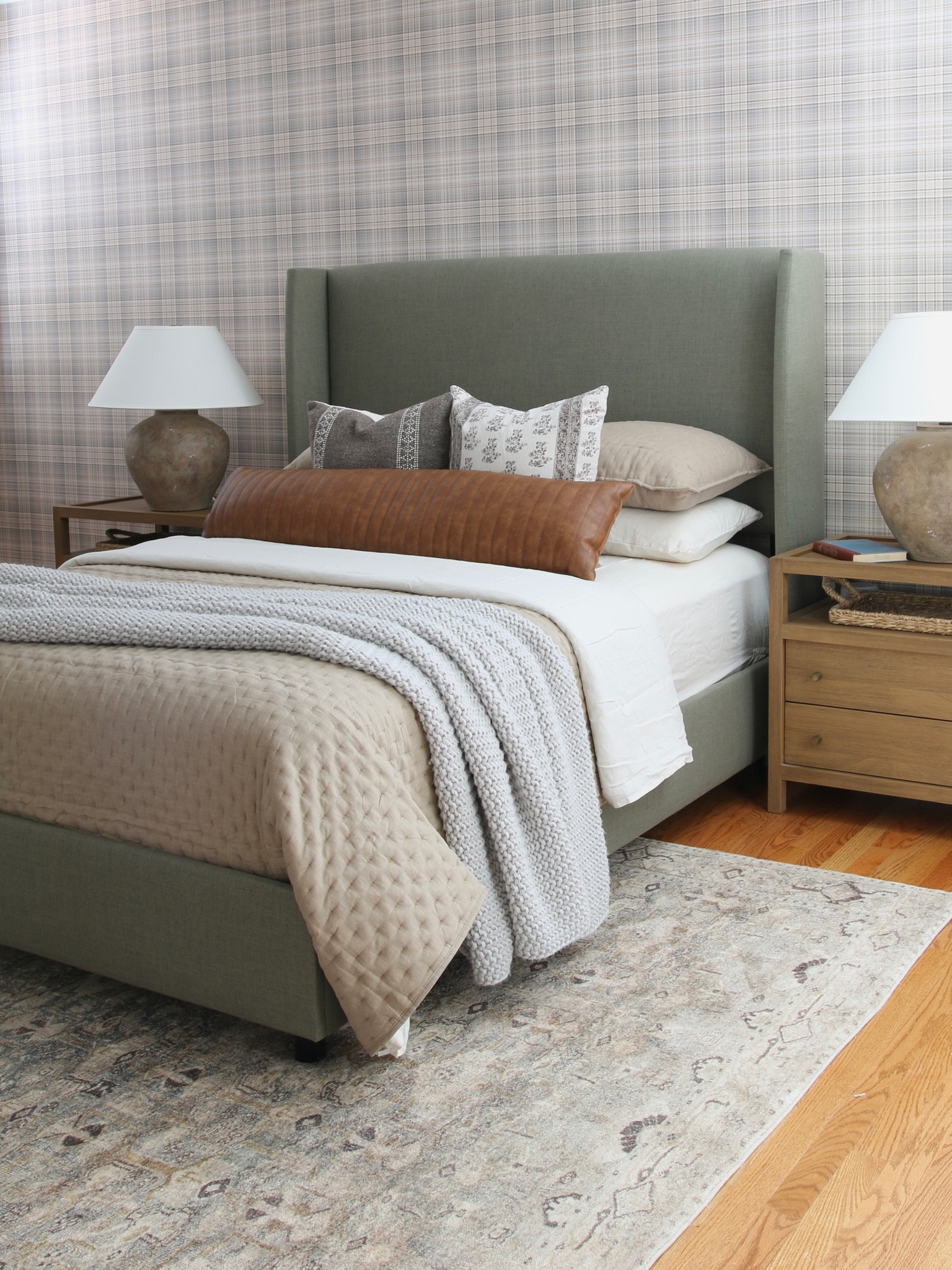 This is how I styled the room when my son moved in 
I used check plaid pre-pasted wallpaper and updated the low profile upholstered bed in green. 
I changed to a solid wood 2 drawer nightstand and textured ceramic table vase on each side of the bed. 
I kept the chunky knit blanket, updated the bedding with a flax linen diamond quilt and linen sheets

#LTKstyletip #LTKFind #LTKhome