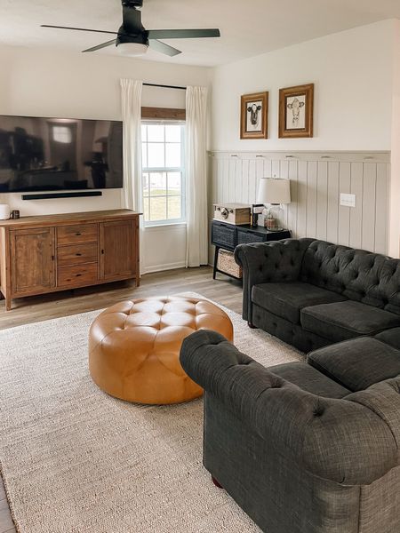 Moody modern farmhouse living room setup. Leather ottoman, dark tuffed couch, jute rug, vertical shiplap and wood accents. 
#modernfarmhouselivingroom
#rugsusa
#juterug

#LTKsalealert #LTKhome