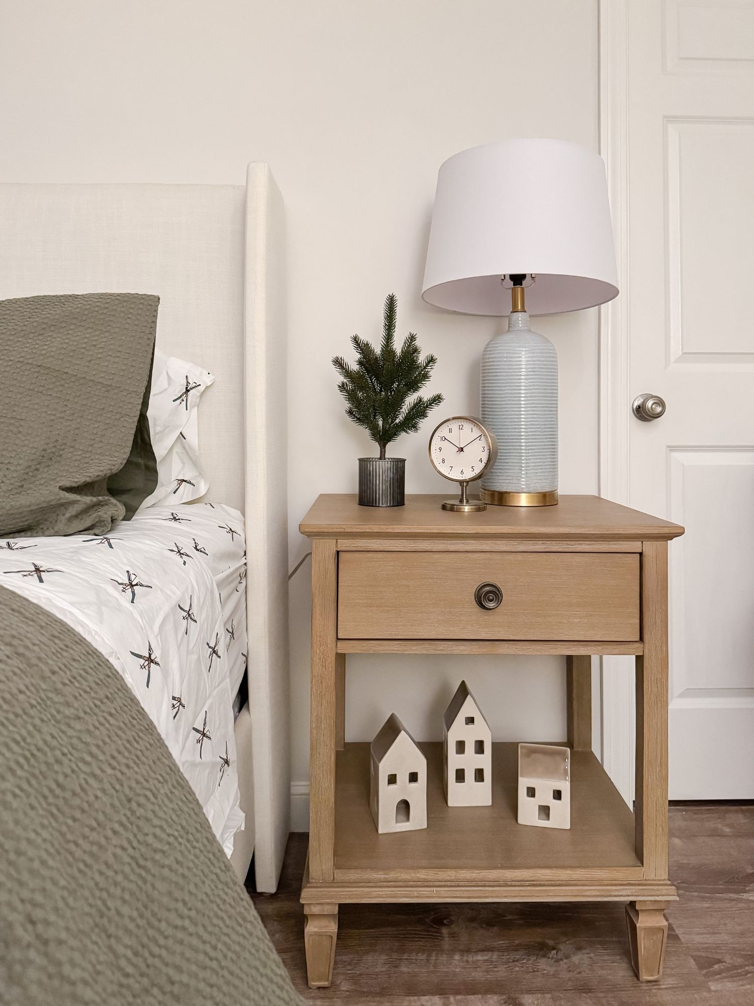 A simple and charming winter bedroom nightstand with a tiny evergreen, vintage clock, and ceramic accents. This styling keeps the guest space festive without feeling heavy or cluttered. winter bedroom, guest bedroom decor, coastal bedroom style, holiday nightstand, neutral winter decor, bedside styling, cozy guest room, coastal winter bedroom, seasonal accents, soft neutral styling, Sherri Calnan Home

#LTKHoliday #LTKHome #LTKSeasonal