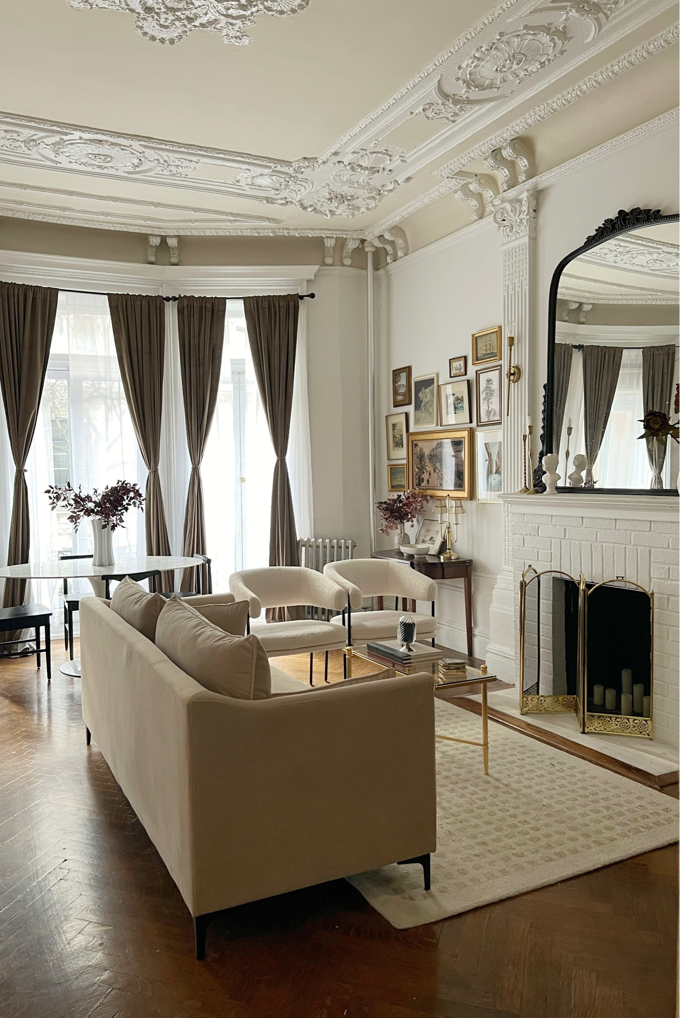 Living/dining room decor and furniture- tan velvet sofa, neutral area rug, gold and glass small rectangular coffee table, white accent chair, black mantle mirror, gold sconces  

#LTKFind #LTKhome #LTKstyletip