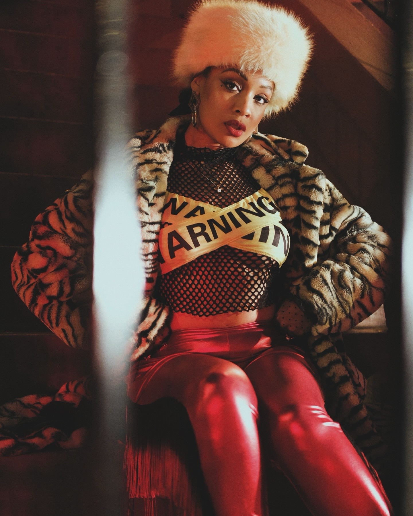 Mob Wife 💂🏽💋 this look is really giving my wife in Jersey had my fur hat which was a question or choice. I’m so happy I made it for this photo Shoot. My fur tiger print floor length coat, red French pants, and this warning top was thrifted 