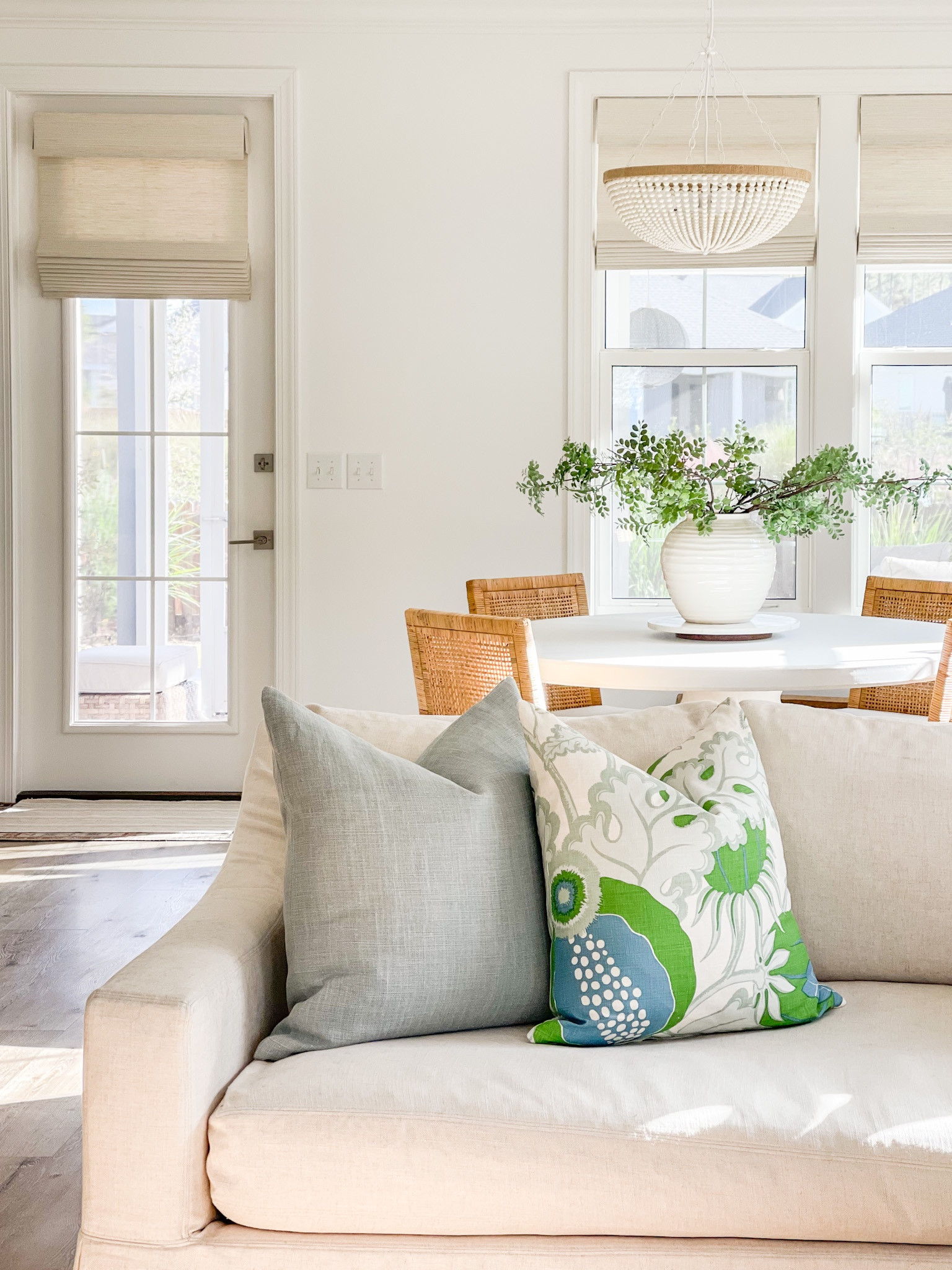 Our Florida living room with linen slipcover sofa, chambray blue linen pillow, blue and green patterned pillow, and a view of our dining room with a white bead chandelier, rattan dining chairs, white concrete dining table, and my favorite faux greenery.
.
#ltkhome #ltksalealert #ltkunder50 #ltkunder100 #ltkstyletip #ltkseasonal

#LTKunder100 #LTKsalealert #LTKhome