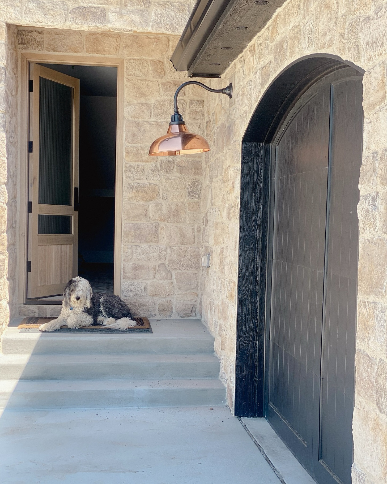 It’s all in the small details! Choosing minor details like light fixtures can seem overwhelming. But they can make the biggest impact. 

This is our side entrance. We went with black arched garage doors. They stand out against the tumbled stone. The white oak reeded glass door provides a soft entrance. 

This show stopper copper exterior light steals the show. Then of course there is the most adorable furry model. 

#home #homeexterior #stone #stoneworks #homesweethome #exterior #exteriordesign #garagedoors #arch #reededglass #exteriordoors #customhomes #customhome #luxuryhome #luxuryhomes #exteriorlighting #copperlights #exteriorlights #sheepadoodle