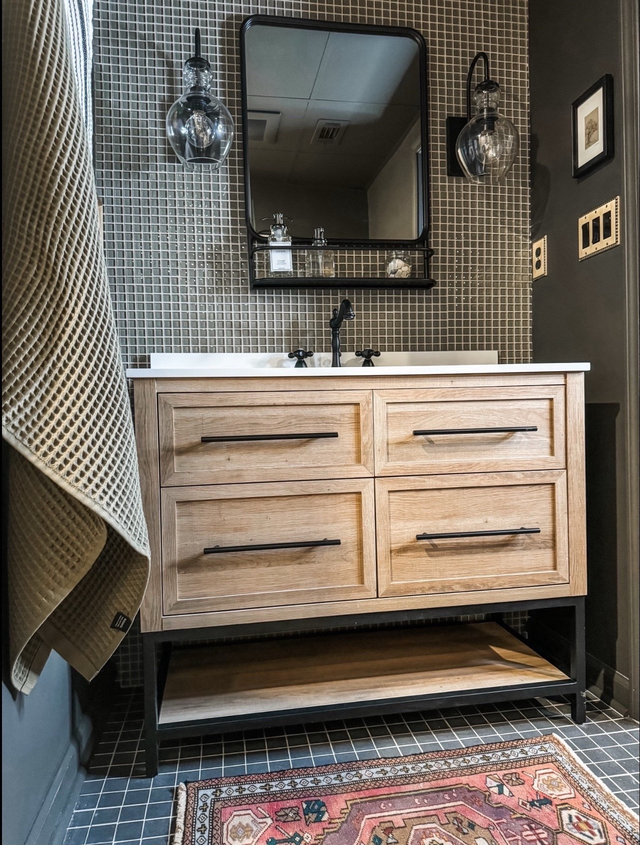 Moody + chic ✨ A matte black faucet anchors the sleek vanity with white countertop and wood cabinetry. Mosaic tile, glass globe sconces, and layered towels provide texture, while fun wall art, including Mona Lisa sipping wine, makes this bathroom unforgettable.
#BathroomInspo #MatteBlackFixtures #WoodCabinetry #MosaicTileDesign #GlassSconceLighting #BathroomDetails #ArtInTheBathroom #eanesinteriors



#LTKvlog #LTKHome #LTKFindsUnder100