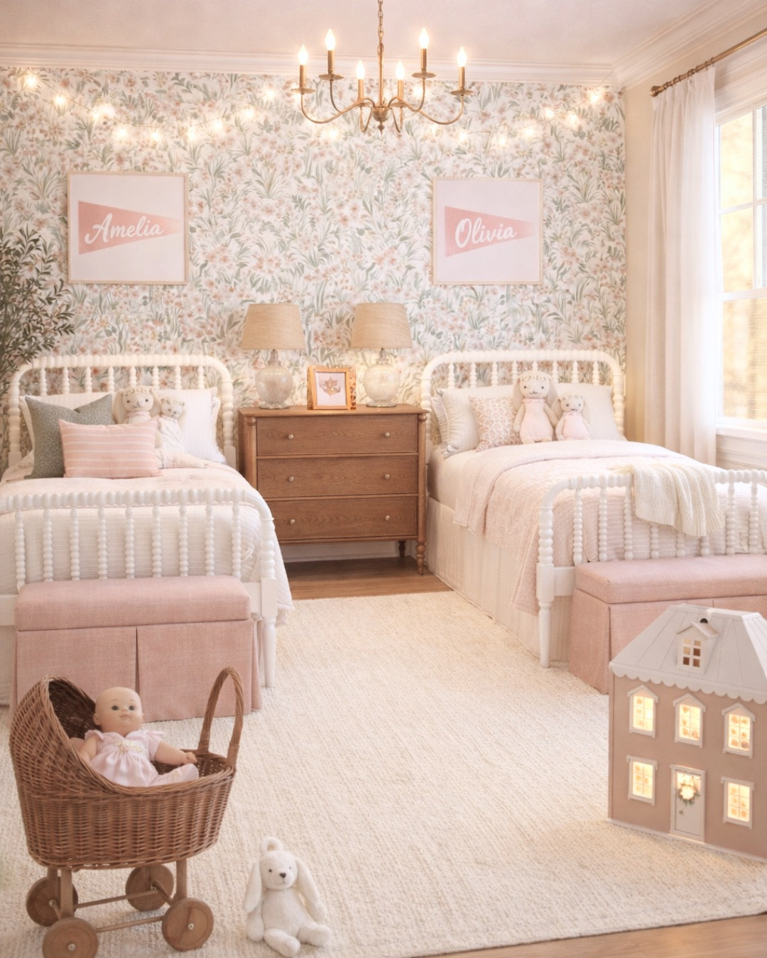 A soft + timeless shared girls bedroom designed with my signature modern classic style 🤍 This space is the perfect blend of feminine, cozy, and functional—featuring matching twin beds, warm wood tones, and the prettiest floral wallpaper for a layered, designer look.

I love how the symmetrical layout creates such a calm and balanced feel, while still giving each side its own personality with personalized name art and layered bedding. The vintage-inspired bobbin beds add so much charm, and the warm wood nightstand grounds the space beautifully.

Details like the blush pink accents, neutral textured rug, woven doll pram, and soft lighting make this room feel inviting, cozy, and full of warmth. The brass chandelier and string lights add that magical glow that makes it feel extra special for little girls.

Perfect for a shared kids room, sisters bedroom, twin girls room, or anyone wanting a feminine, traditional space that will grow with them over time 🤍

Shop all of my sources for this space below ✨

#ltkhome #ltkstyle #girlsroom #sharedkidsroom #twingirlsroom #kidsroomdecor #modernclassic #traditionalhome #grandmillennial #floralwallpaper #bedroominspo #interiordesign #femininehome #pinkdecor #layeredhome #neutralhome #cozyhome #classicinteriors #kidsbedroomideas

#LTKBaby #LTKHome #LTKKids
