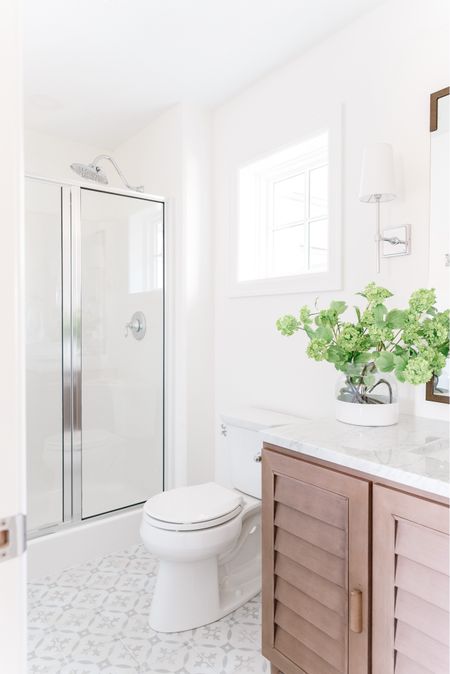 All the details of our small guest bathroom remodel in Omaha! Items include a louvered wood vanity with a Carrara marble countertop, chrome bath faucet, mirror with bracket corners, paint dipped vase with faux viburnum stems, silver wall sconces, and chrome bathroom hardware. See even more details here: https://lifeonvirginiastreet.com/small-guest-bathroom-remodel-reveal/

.
Amazon home decor, target home, target finds, mcgee and co mirror, studio mcgee mirrors, amazon faucets, amazon bathroom accessories, bathroom vanity lighting, wall sconce, bathroom faucet, bathroom flooring, bathroom ideas, bathroom inspiration, amazon bathroom, bathroom hardware, bathroom accessories, bathroom remodel, cement tile, wood vanities, white bathroom, wall sconces, chrome light fixtures 

#ltksalealert #ltkhome #ltkfindsunder50 #ltkfindsunder100 #ltkstyletip #ltkseasonal #ltkkids #ltkfamily 

#LTKHome #LTKSeasonal #LTKSaleAlert