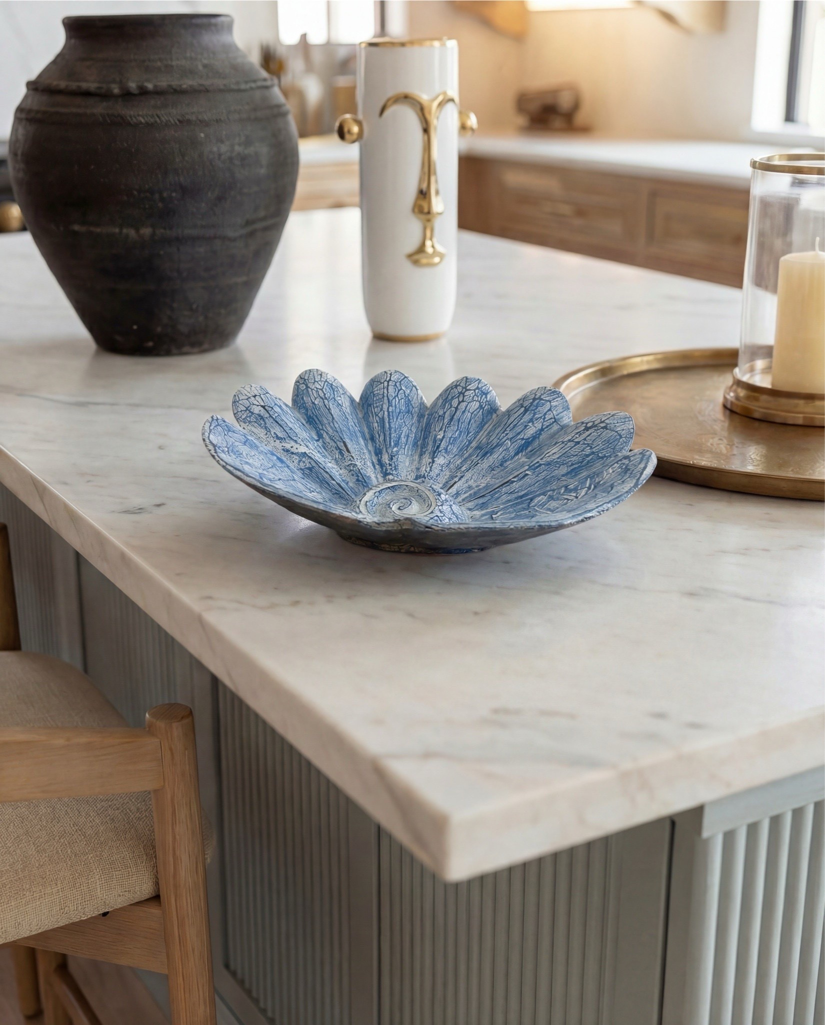 This kitchen feels warm, elevated, and quietly luxurious. Natural wood cabinetry and exposed ceiling beams bring a grounded, organic warmth, while crisp marble surfaces and a sculptural black range add contrast and refinement. Soft brass accents throughout—hardware, lighting, and fixtures—create a subtle glow that ties everything together, making the space feel timeless yet current.

The styling is restrained and intentional—layered neutrals, classic materials, and sculptural details that feel collected rather than styled. It’s a kitchen designed to be both beautiful and deeply functional, where everyday moments feel considered.

Shop the Look:

• Black range stove with brass knobs and handles

• Brass pendant light with white glass shade
• Brass wall sconces with globe shades
• Upholstered wood counter stools (light wood + neutral fabric)

• Vintage-style runner rug (soft blue and neutral tones)
• Black ceramic decorative vase
• White ceramic vase with brass detail
• Blue sculptural ceramic bowl
• Brass tray with glass hurricane candle
•Brass serving tray decor
•Black terracotta vase jar


#LTKSaleAlert #LTKHome