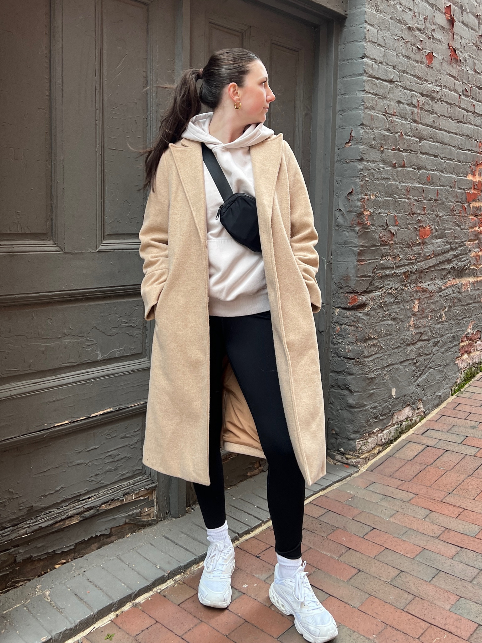 Casual winter hoodie, leggings, lululemon belt bag, white sneakers, and tan wool coat outfit