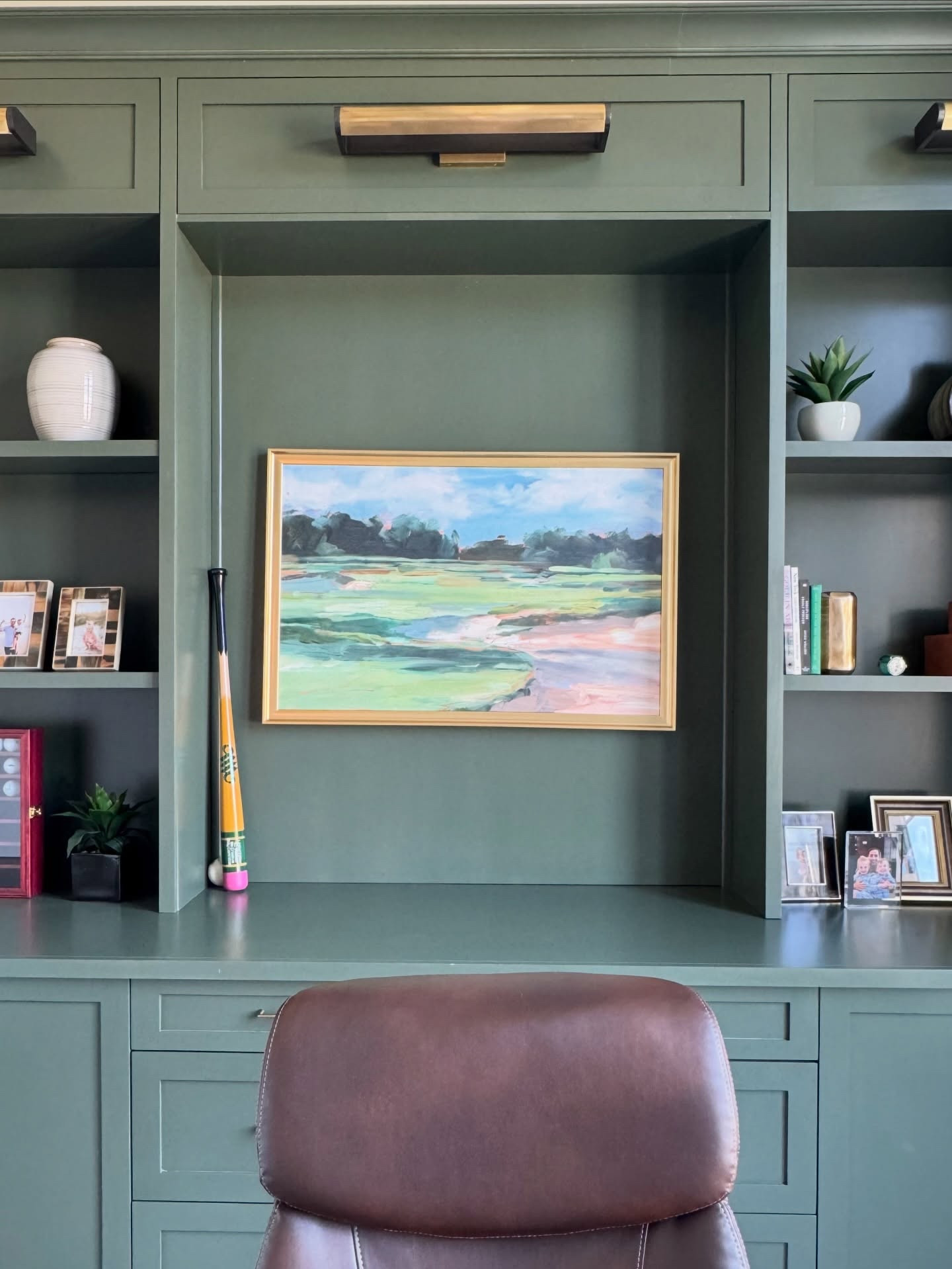 Office details 🤍 My husband's home office redesign this year has to be one of my favorite projects that we've ever done. The moody green cabinets pushed me out of my usual light and bright palette and were so fun. I put so much effort into designing this space from picking the most gorgeous lighting to the hidden panel-ready wine fridge to the pull-out printer shelf. It's always so fun to see your vision come to life. Comment SHOP for the links to the sources for this space. The paint color is Benjamin Moore Vintage Vogue.