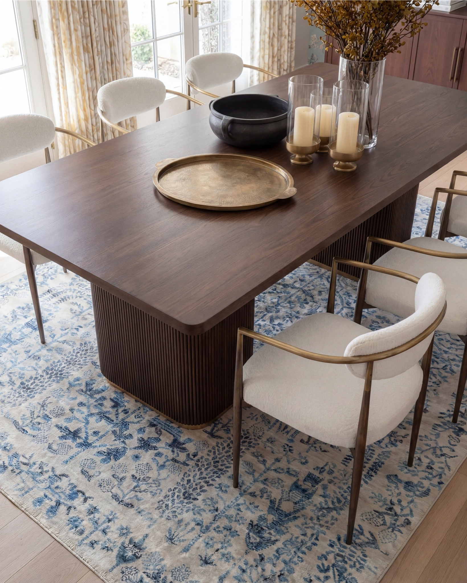 This dining room feels like a pause in time—in the best way. The soft blue floral wallpaper instantly sets the mood, while the exposed wood beams ground the space and keep it from feeling too formal. It’s classic, but approachable.

What really makes this room work is the balance: the sculptural wood dining table anchors everything, while the light, upholstered chairs keep it airy and inviting. Brass accents add just enough warmth, and that blue patterned rug quietly ties the walls to the floor without competing for attention.

It’s elegant, intentional, and designed for long dinners that turn into even longer conversations.

Shop the Look:
• Solid wood dining table
• Upholstered dining chairs with brass frames
• Blue floral wallpaper
• Blue patterned traditional rug
• Wood ceiling beams
• Glass candle holders
• Black ceramic bowl decor
• Black ceramic vase
• Brass serving tray
• Solid wood buffet console
• Solid oak tall cabinet
• Black ceramic decor bowl
• White decor books
• Black table lamp, white fluted decor bowl
• Neutral linen curtains
• Wood display cabinet with glass doors

#LTKhome #LTKsale #LTKstyletip