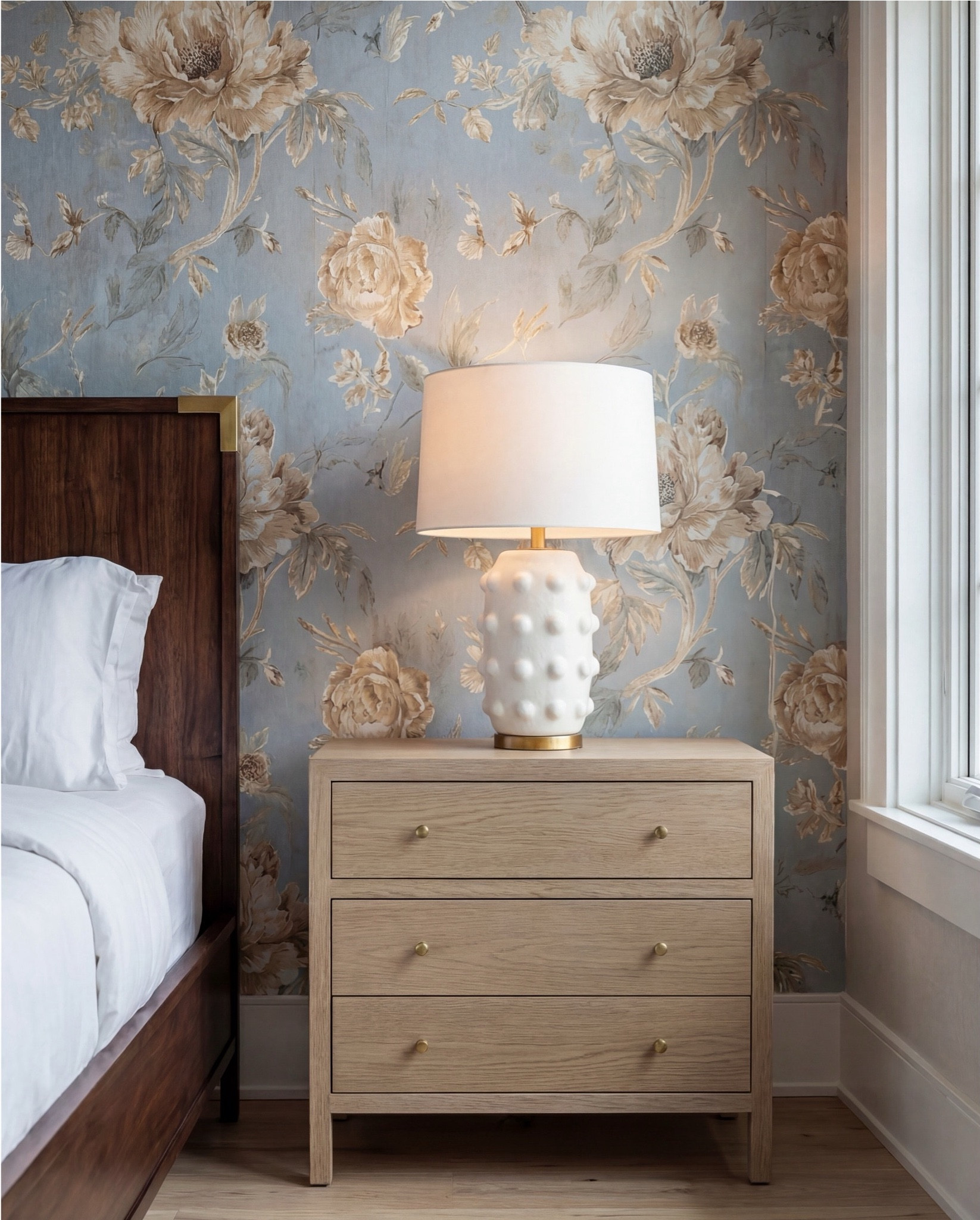 Warm, textural, and effortlessly elevated — this bedroom blends deep walnut wood, soft caramel tones, and a blue floral statement wall for a cozy, high-end retreat. The dark walnut bed anchors the room with rich grain detail, while the chunky knit throw and camel bouclé ottomans add warmth and dimension. Layered neutral pillows soften the palette, and the vintage-washed blue rug ties everything together with a subtle, timeworn look. This is the perfect balance of modern comfort and classic pattern.

Shop the Look:
• Walnut wood panel bed with brass accents
• Camel bouclé cube ottomans
• Blue floral wallpaper with beige undertones
• Chunky hand-knit caramel throw
• Textured neutral throw pillows
• Light oak nightstands
• Sculptural white ceramic table lamps
• Round gold beaded mirror
• Blue distressed vintage-style area rug
• Woven basket with knit accent throw


#LTKSaleAlert #LTKHome