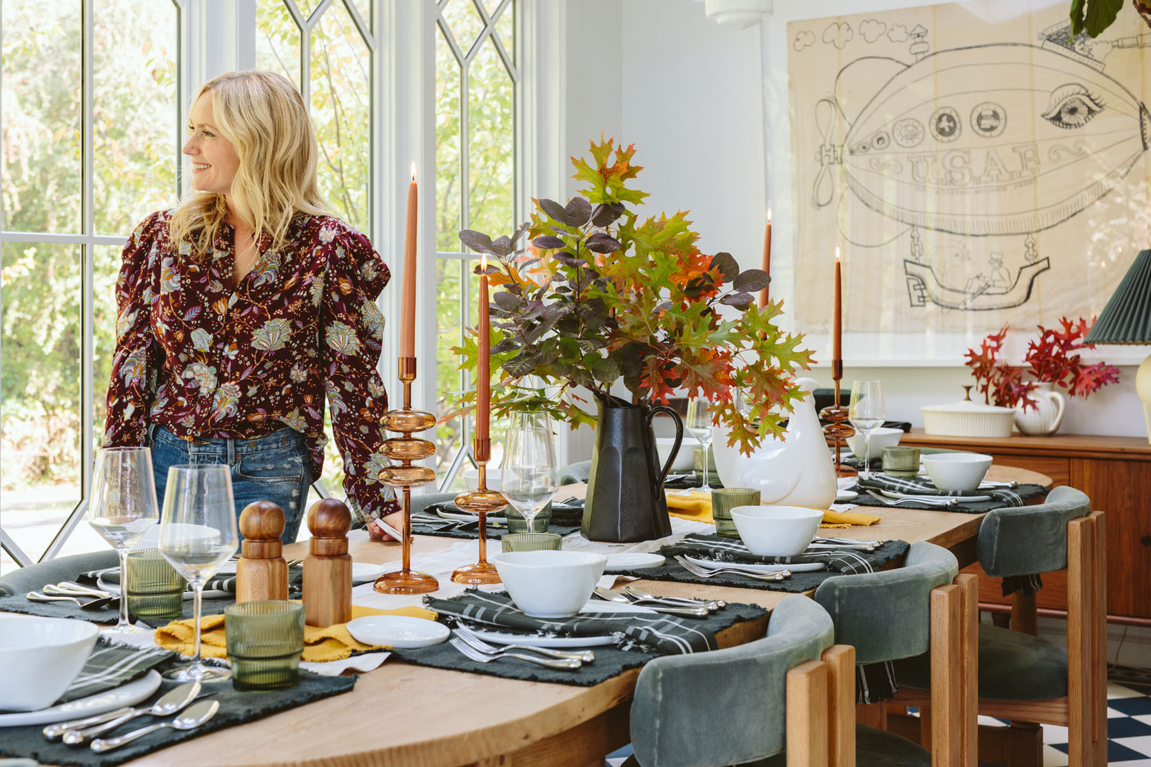 As you can see, we have some fall motifs – the plaid runner, the amber candle holders (and candlesticks), one mustard napkin, some fall leaves and you know, THE HUGE CERAMIC TURKEY. But beyond that, it’s just white plates, with green napkins, glassware, and pretty silver flatware. All these things work year-round in my house (which leans green/blue modern farmhouse).

I think it’s fun to think of some of these colors, patterns, and elements as “seasonal indicators”. Fall branches + mustard + a warm plaid + Turkey = Thanksgiving. Some scattered pine cones or wicker/wood elements for turkey day and you get the same “vibe”.