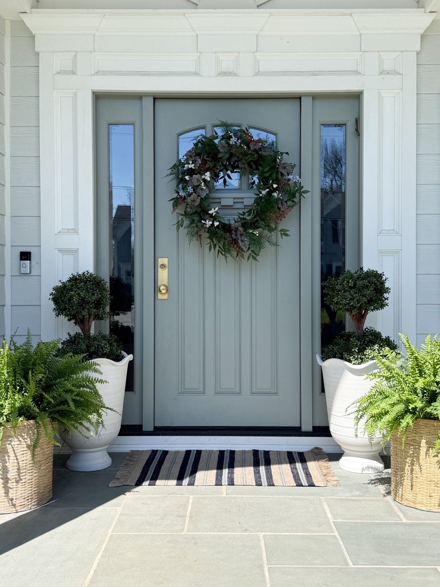 I love how this entry comes together with just a few really thoughtful pieces that all play off each other. The greenery wreath creates a soft focal point on the door, while the mix of woven baskets and classic urn planters adds that layered contrast I’m always drawn to. Even the striped rug ties everything in and makes the whole space feel welcoming without overcomplicating it.

front door decor ideas, greenery wreath styling, outdoor planters front porch, woven planter baskets, classic urn planters, layered front porch decor, entryway curb appeal, neutral exterior design, striped outdoor rug, welcoming front entry, outdoor styling ideas girlonthehudson

#LTKSeasonal #LTKHome