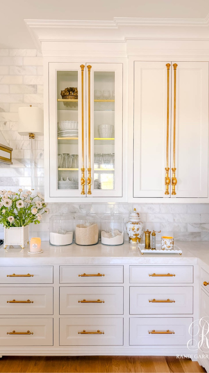Flanking the stove, I styled these gorgeous, light pink ranunculus in white and gold cache pots. I used 8 ranunculus stems in each arrangement. They frame the range and add some charm and whimsy to the room.

Scent is such an important part of styling for me. These Ginori 1735 candles add a soft, refined aroma throughout the kitchen, while Coconut Papaya candles bring the most beautiful tropical sweetness that coordinates perfectly with the peachy pink florals.

There are charming scalloped details throughout the kithchen— on the candle trays, scalloped vignette tray, and even the soap tray  Those soft curves feel feminine and playful, balancing the more structured elements in the kitchen.

#LTKHome #LTKSeasonal