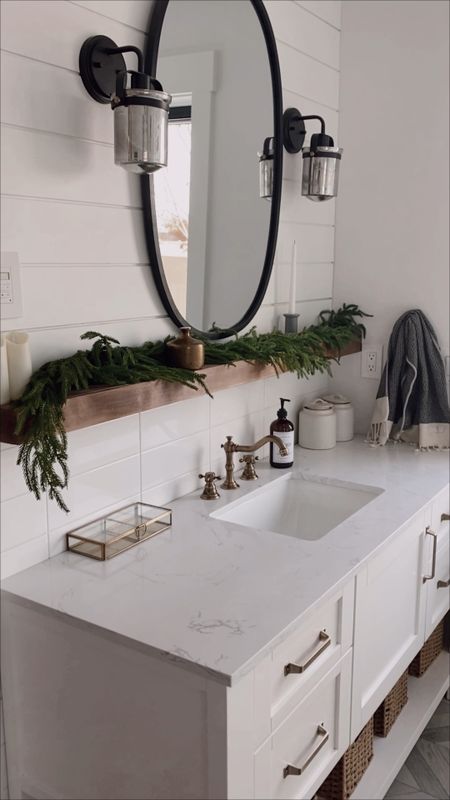 Adding a little holiday cheer to our bathroom | brass faucets, brass wall mounted tub filler, garland, white vanity, brass drawer pulls, oval mirror, brass chandelier 

#LTKHoliday #LTKSeasonal #LTKhome