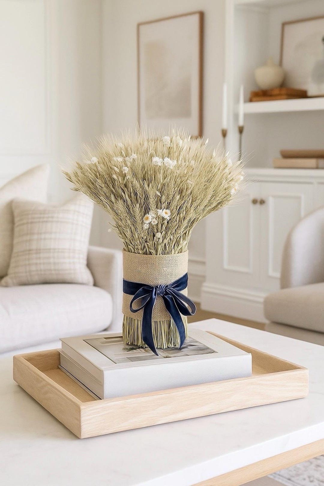 Add a touch of rustic elegance to your home with the Velvet Somerset centerpiece. Crafted from dried green wheat, avena oats, and delicate ammobium daisies, this handcrafted arrangement blends natural texture with refined charm. The burlap wrap and navy velvet bow create a beautiful balance of farmhouse warmth and classic style—perfect for styling on tables, counters, or seasonal displays. #ltkhome #ltkstyle #driedflowers #farmhousedecor #rusticelegance #botanicaldecor #cottagehome #naturaldecor

#LTKSeasonal #LTKHome