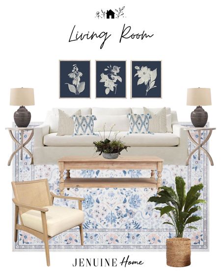 Light living room. Coastal living room. Light blue Rifle Paper CO rug. Floral rug. White traditional couch. White and grey striped throw pillow. Blue and white pillow. Light wooden side table. Black traditional lamp. Navy floral art. Cane backed arm chair. Basket. Faux plant. Traditional living room.Grand  living room. Light coffee table. Faux orchid decor. 