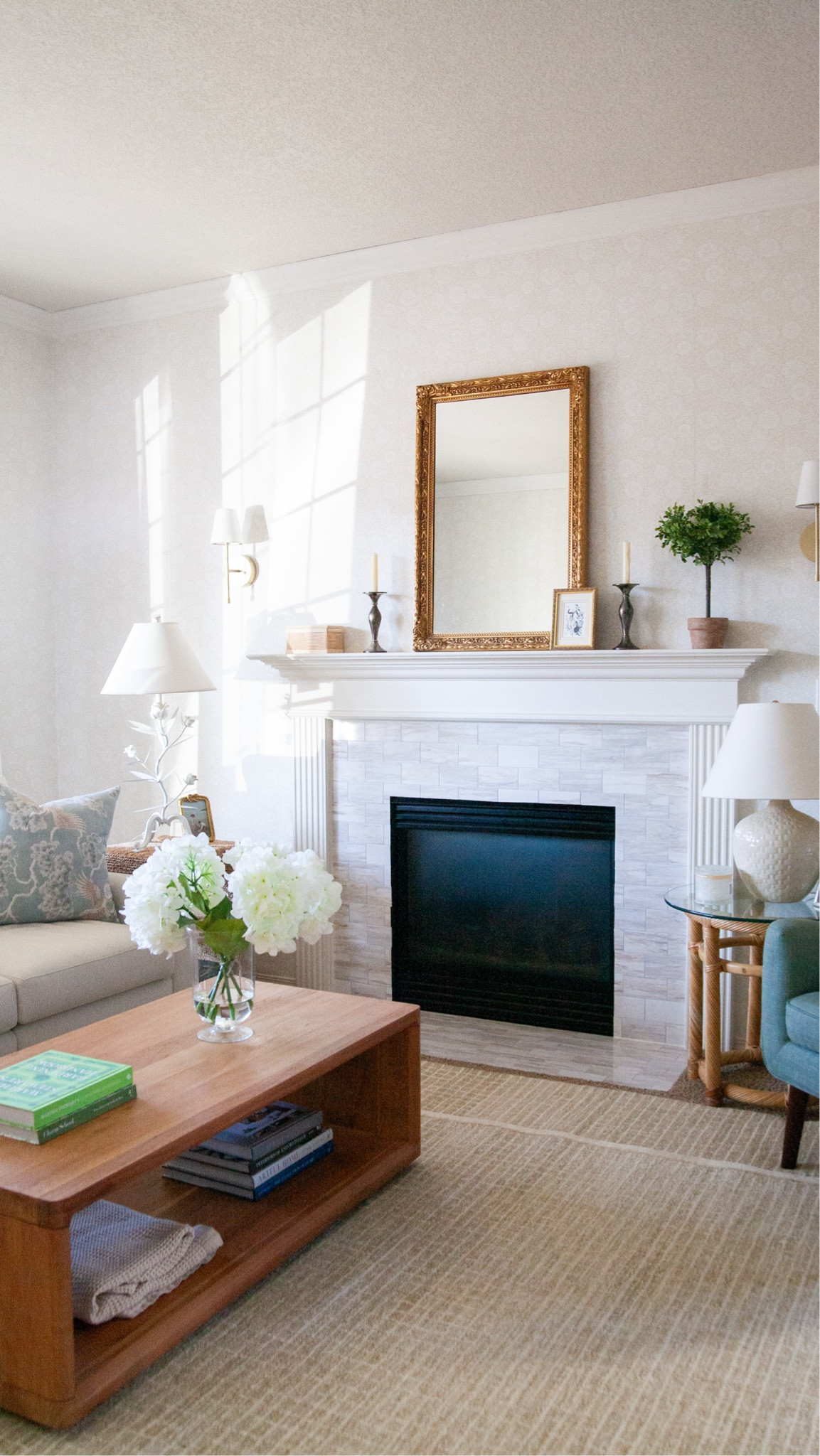 So excited for this reveal because this room has come such a long way. My friend's living room was just not giving the style that she wanted for her fun family-friendly home. 

First I taught her to wallpaper: we covered the entire walls in this lovely little floral pattern from A-Street Prints. 

We replaced the builder blinds with these lovely natural bamboo roman shades and linen curtains (use my code Suzannah26 for 26% off!), added a much larger wool rug, of course some fun accessories including white and brass and gold, and some warm wood and bamboo and rattan tones because there were so many light colors in here. 

My friend loves a light and fresh style and this is her front room so it's very important for it to feel welcoming and like her.  We are so happy with how this room turned out and love the texture the wallpaper added!

#LTKHome
