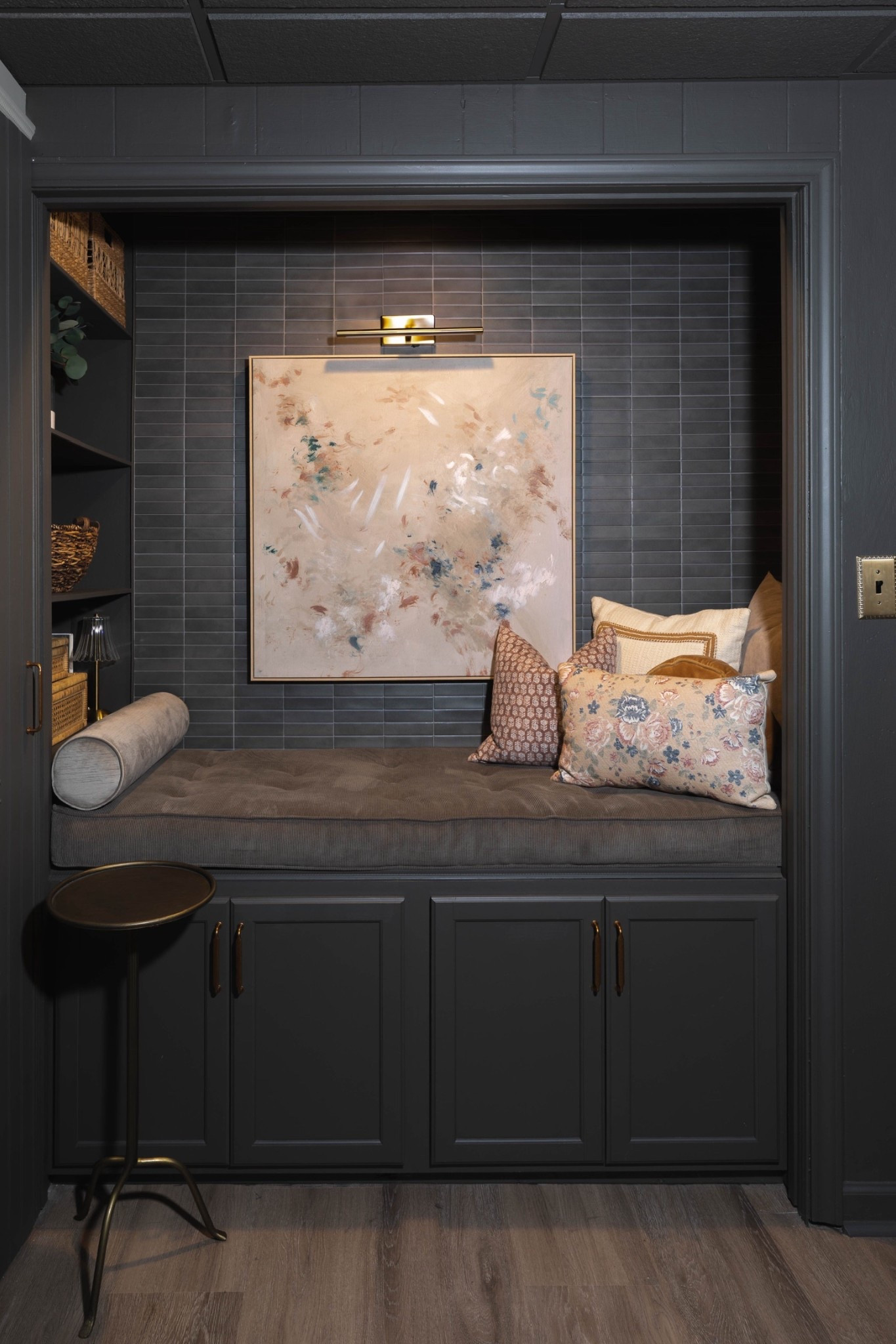 A moody nook with layers of texture ✨ Dark built-in cabinetry with brass hardware sets the tone, styled with woven baskets, rattan storage boxes, and a glass vase with greenery. A tufted bench cushion with bolster pillow adds comfort, while the brass side table and abstract wall art under a picture light bring the perfect finishing touches. 🌿

#CozyNook #BuiltInCabinetry #WovenBaskets #RattanStorage #GlassVase #GreeneryDecor #TuftedCushion #BolsterPillow #AbstractArt #PictureLight #BrassAccents #eanesinteriors

#LTKHome #LTKFindsUnder100 #LTKOver40