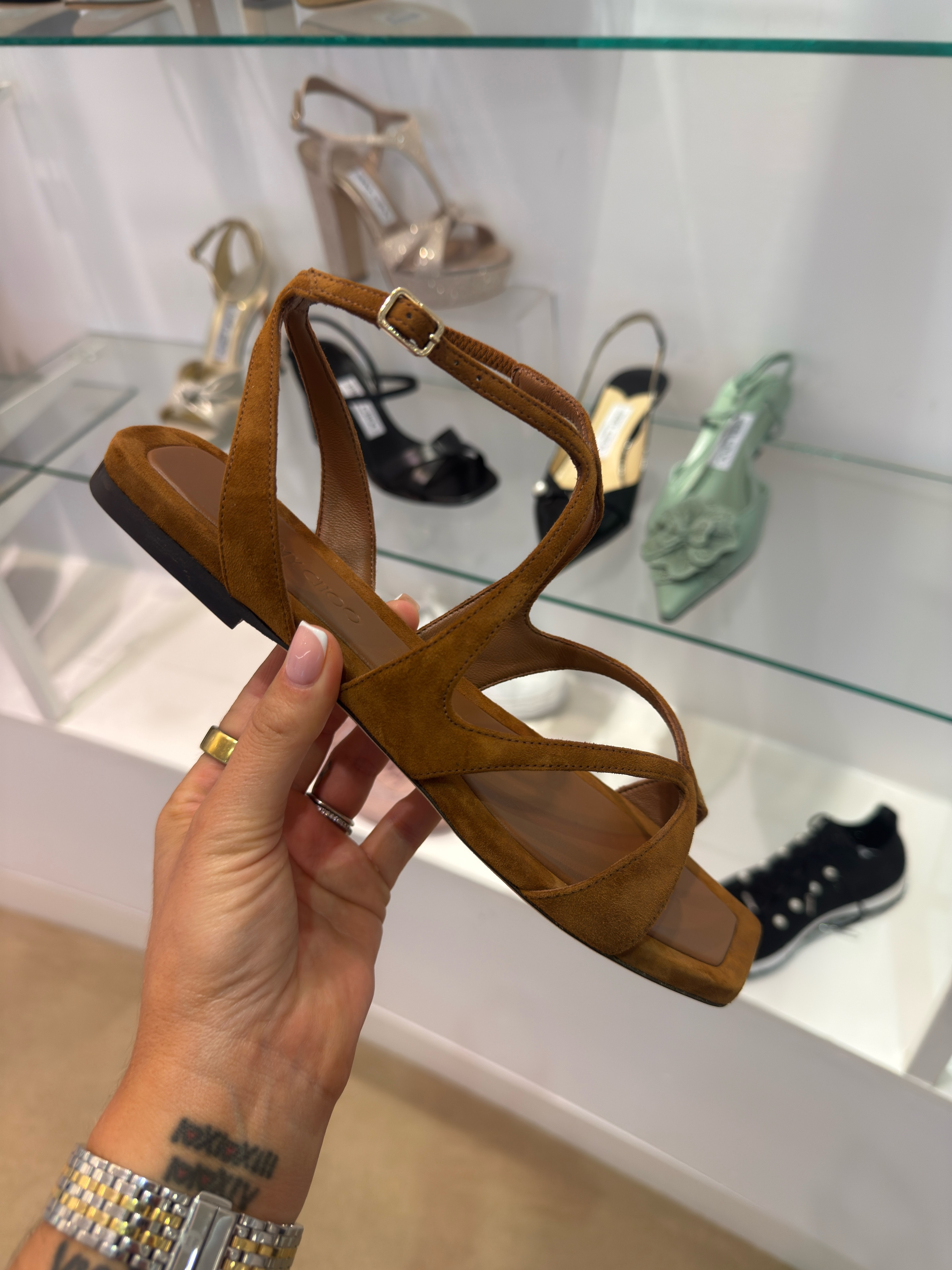 The flat sandal I've been recommending to every client who says they want something that looks expensive but won't destroy their feet by noon.
Jimmy Choo's Ayla Flat in tan suede is a cross-strap sandal with a square toe and a gold buckle at the ankle — clean, architectural, and the kind of neutral that works harder than it looks. Tan suede reads warm without being heavy, which is exactly what you want when it's 90 degrees and you still need to look pulled together.
At $895 on sale, yes — this is a considered purchase. But this is the shoe you wear with wide-leg linen trousers, a midi skirt, a summer dress, or straight-leg denim and a crisp white shirt. It doesn't need help. It just works.
Fit note: suede runs slightly narrow through the cross straps on some fits — if you're wider through the forefoot, size up before you commit. 

 #shoes #jimmychoo