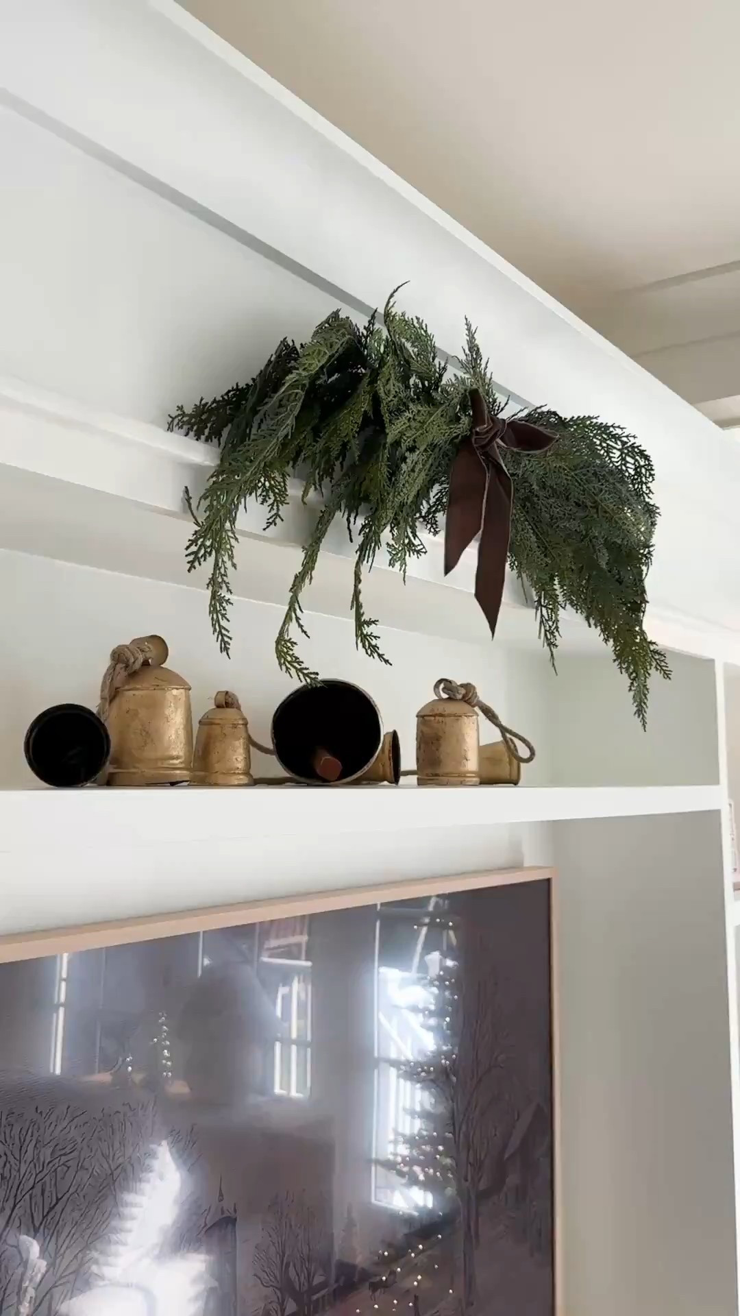 I used a command hook to hang this cedar swag on my media center - would also be beautiful on a mirror or lathe pieces of art. Finish with a velvet ribbon! On my narrow shelf, I layered brass holiday bells 

#LTKSeasonal #LTKHome #LTKHoliday