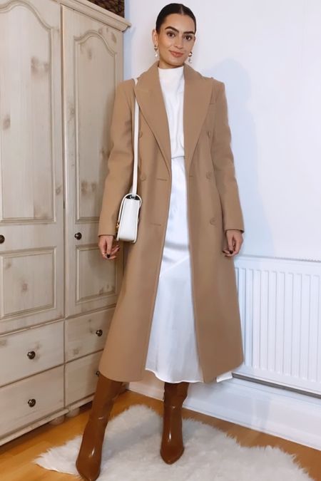 Winter whites outfit idea 🤍

Camel coat, mock neck sweater, satin midi skirt, Maje clover bag, brown knee high boots

#LTKSeasonal
