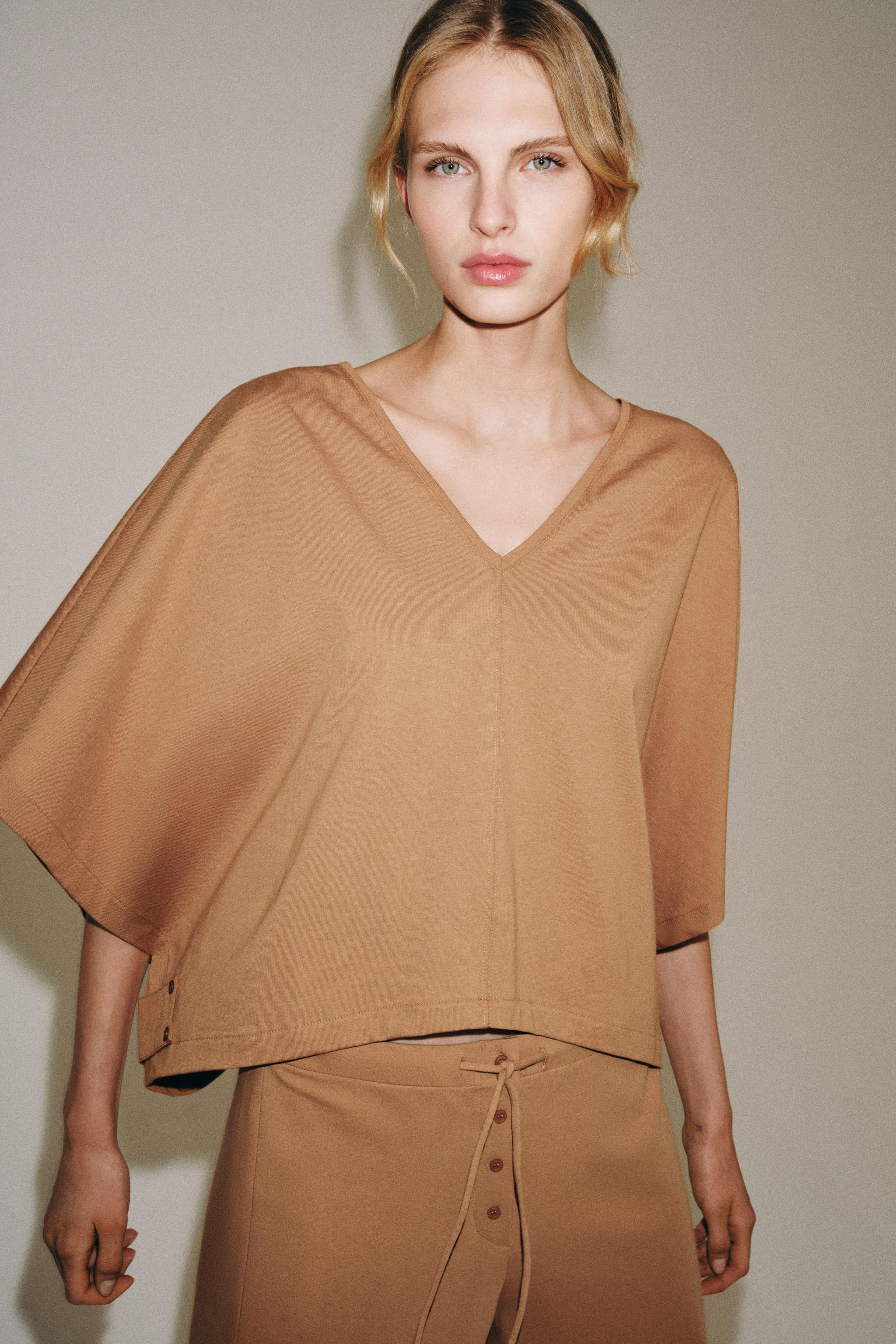 T-shirt made with main cotton yarn fabric. V-neck and short cape sleeves. Asymmetrical hem with m... | Zara US