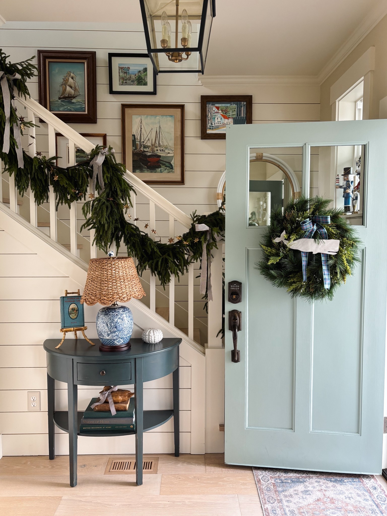 Our cottage entry at Christmas 

Table, scalloped seagrass lampshade, chinoiserie blue and white lamp, bamboo easel, lantern, metal whale on wreath with plaid ribbon, rattan mirror, Checkered stocking and more 

#LTKSaleAlert #LTKHoliday #LTKHome