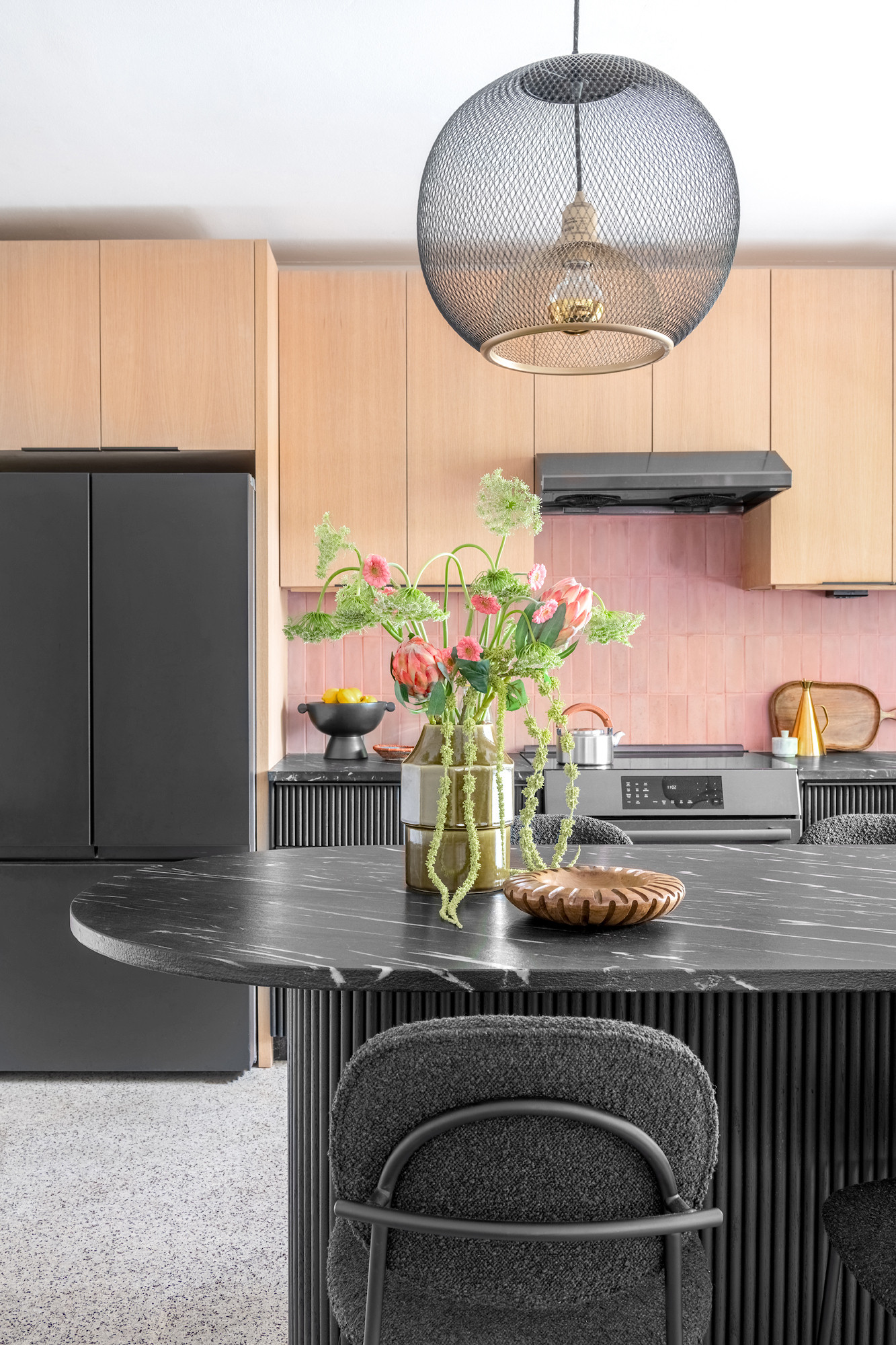 This pink, mid-century modern-inspired kitchen combines bold design choices, functional elegance, and a playful atmosphere that invites creativity. Inspired to flow with the rest of the house, we balanced contrasting materials soft pink tiles, black fluted cabinetry, and light wood upper cabinets to create a harmonious yet striking space. 

 #LTKHome