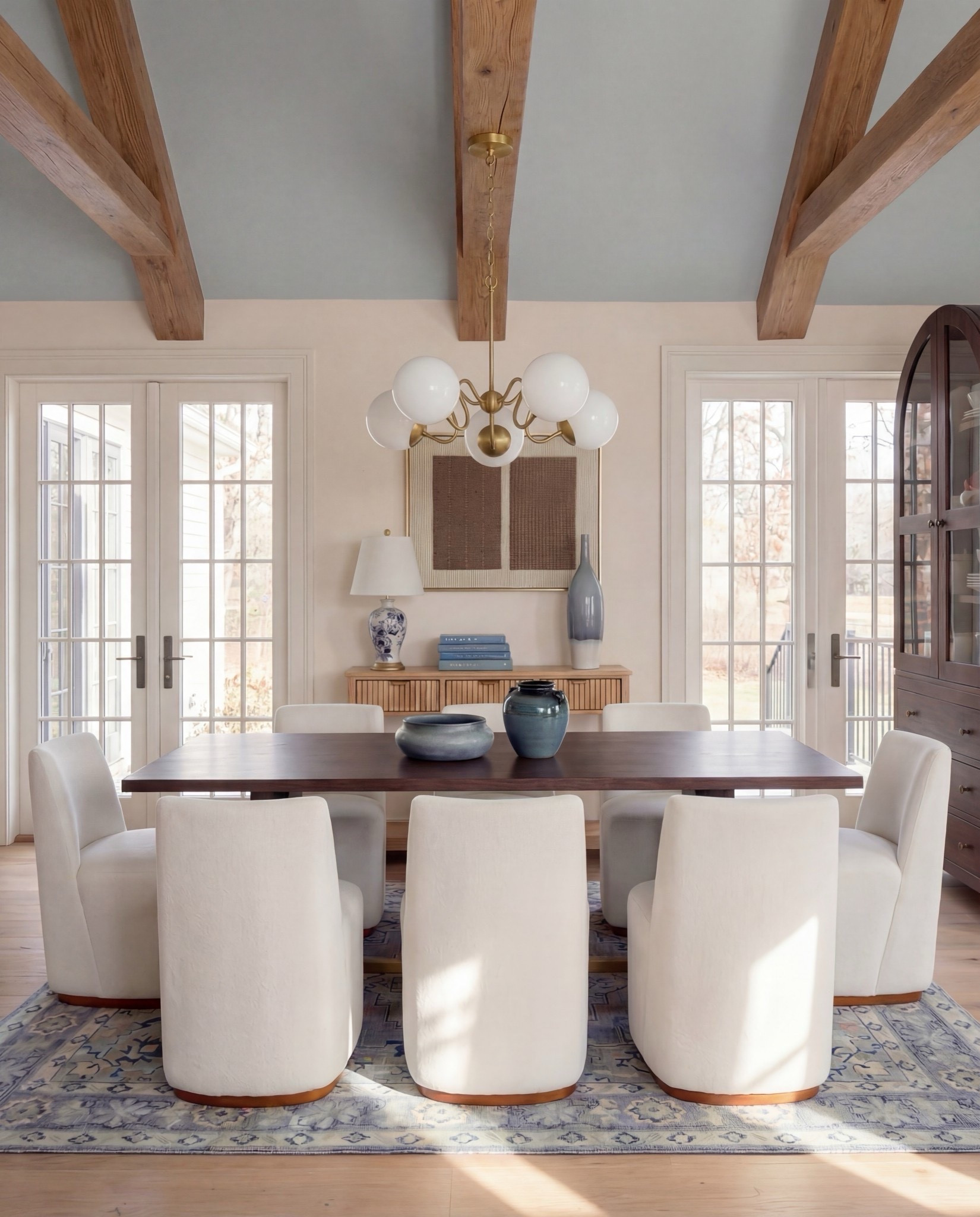 
Shop the Look:
• Dark wood rectangular dining table
Globe ball chandelier light
Brown wall art
• Curved ivory upholstered dining chairs (wood base)
• Blue ceramic decorative bowl (table centerpiece)
• Blue terracotta  vase 
• Blue patterned area rug
• Light wood sideboard with fluted drawer detail
• Blue-and-white ceramic vase (sideboard)
• Blue table lamp with white shade
• Stacked books + candle decor
• Framed landscape wall art (set of two)
• Dark wood arched china cabinet with glass doors
• White ceramic floor vase
Blue decor books
• Exposed wood ceiling beams
• Soft blue ceiling paint
Tall blue floor vase 

#LTKSaleAlert #LTKHome #LTKSpringSale