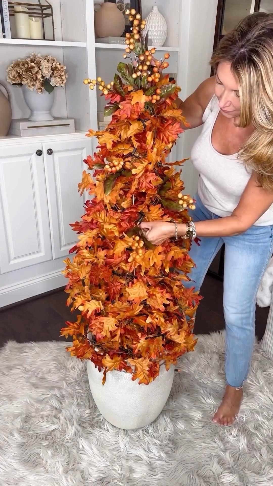 DIY Tomato Cage Fall Topiary Tree 🍂 instantly transforms your space with autumn vibes effortlessly and affordably! 

Elevate your seasonal decor with this chic DIY hack, turning a garden center tomato cage into a high-end designer-style fall topiary. Add a touch of elegance while saving money and bringing pretty fall flair to your home this season! I absolutely love how this tree instantly adds a touch cozy fall ambience to my home. 

Materials: Tomato cage, planter, leaf garland, string lights, berry accents. Suggested for indoor use or covered porch. 

Instructions: 
1. Secure tomato cage onto planter or tuck inside a planter or urn. Use a zip tie or rubber band to fasten the top ends together.
2. Wrap and tie cage with leaf garland until completely covered. I used 5- 6ft garlands. I wanted full coverage and a lush layered look. 
3. Add string lights for a warm glow.
4. Tuck in berry accents for texture.
5. Enjoy your cozy fall decor! 🍁


#LTKHome #LTKVideo #LTKSeasonal