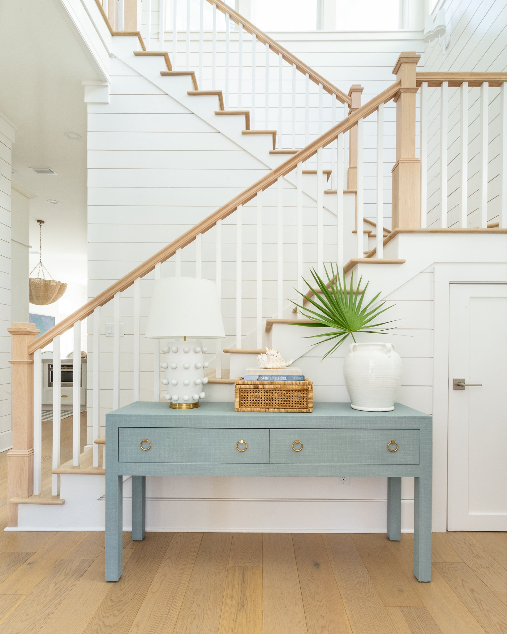 Our coastal summer entryway including a blue linen console table, circle dot lamp, rattan storage box, coastal coffee table books, a seashell and a fan palm in an oversized white ceramic vase. This is a fresh cut fan palm but I’m also linking a faux version I like.
.
#ltkhome #ltkseasonal #ltkfindsunder50 #ltkfindsunder100 #ltksalealert console table styling, entryway decor, foyer tables, Serena & Lily vibes

#LTKSeasonal #LTKSaleAlert #LTKHome