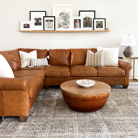 Who doesn’t love a clean living room? My modern living room has a neutral theme with the brown leather couch and table accented with beige and patterned white pillows. And the picture ledge is perfect for  easily changing out photos year round. House reno, home goods, circle wood coffee table

#LTKhome