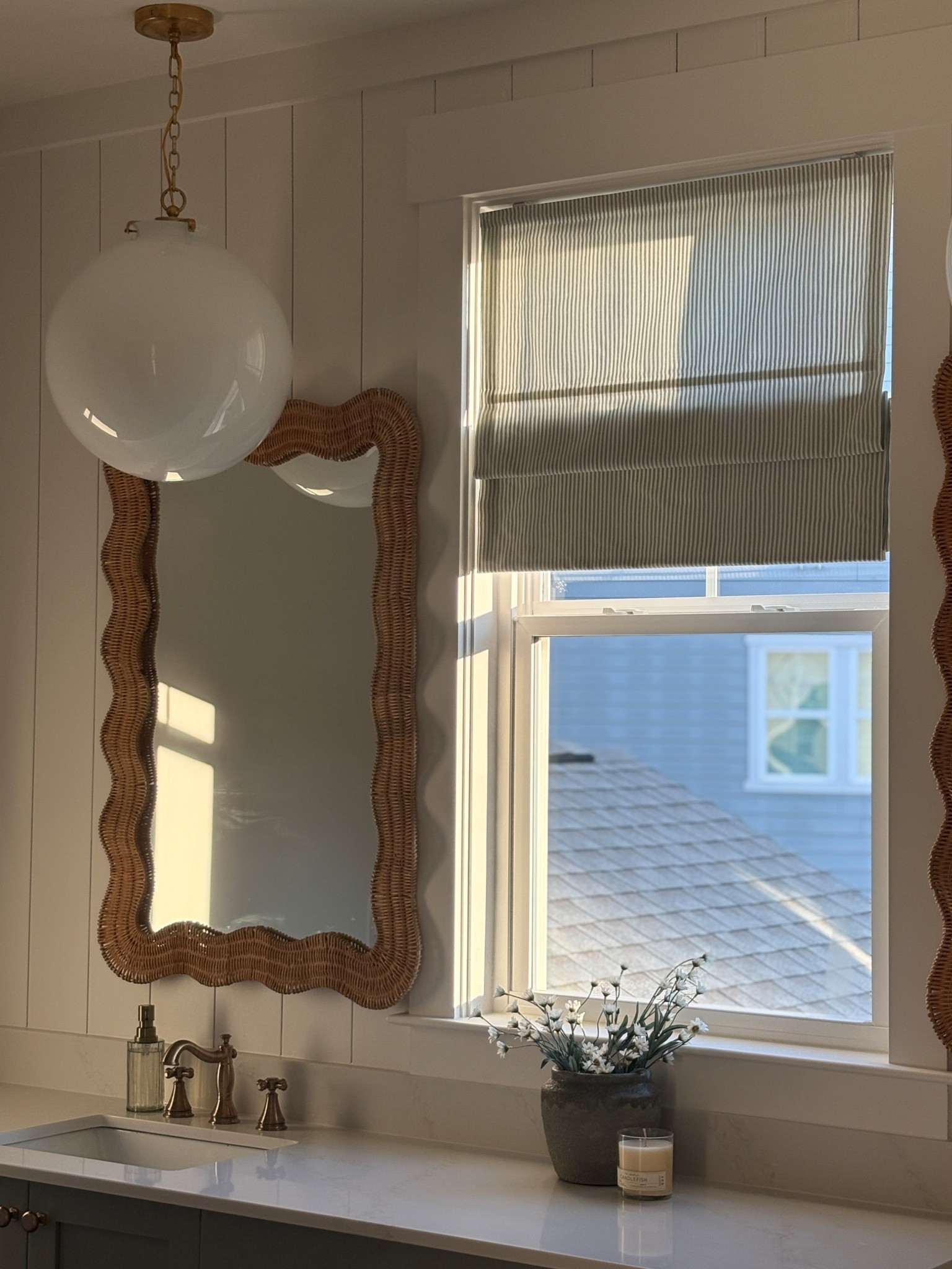 Golden hour glow ☀️✨
This cozy corner in our master bathroom proves that simple textures make the biggest impact — woven rattan, brass accents, and soft striped roman shades bring warmth and timeless charm to this bath. 🤎

Shop the look:
🪞 Wavy rattan mirror
💡 Globe pendant light
🚰 Brass faucet set
🕯️ Neutral countertop accessories

#HouseOfSaintDesign #HomeDetails #CozyBathroom #TimelessDesign #NeutralHome #RattanMirror #BrassAccents #BathroomInspo #ClassicCoastal #InteriorDesignIdeas 

 #LTKHome
