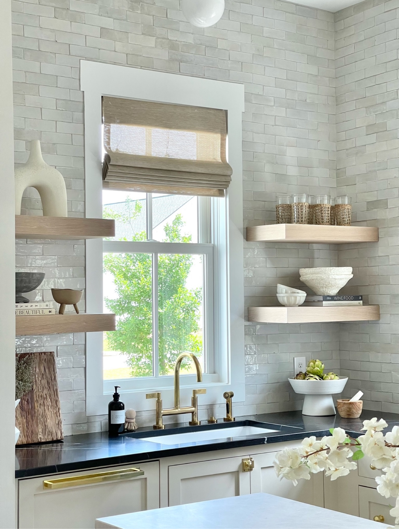 Spring kitchen decor, rattan glasses, paper mache bowl, hand soap, brass faucet, white footed bowl, white oak kitchen shelves, window shades, farmhouse kitchen sink 

#LTKsalealert #LTKhome #LTKSeasonal