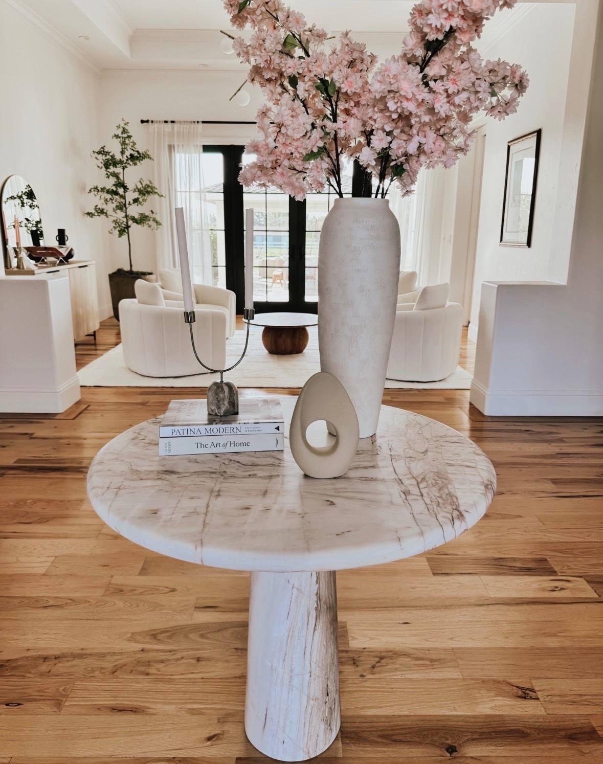 Entry way pedestal table decorated with branches and candles 

