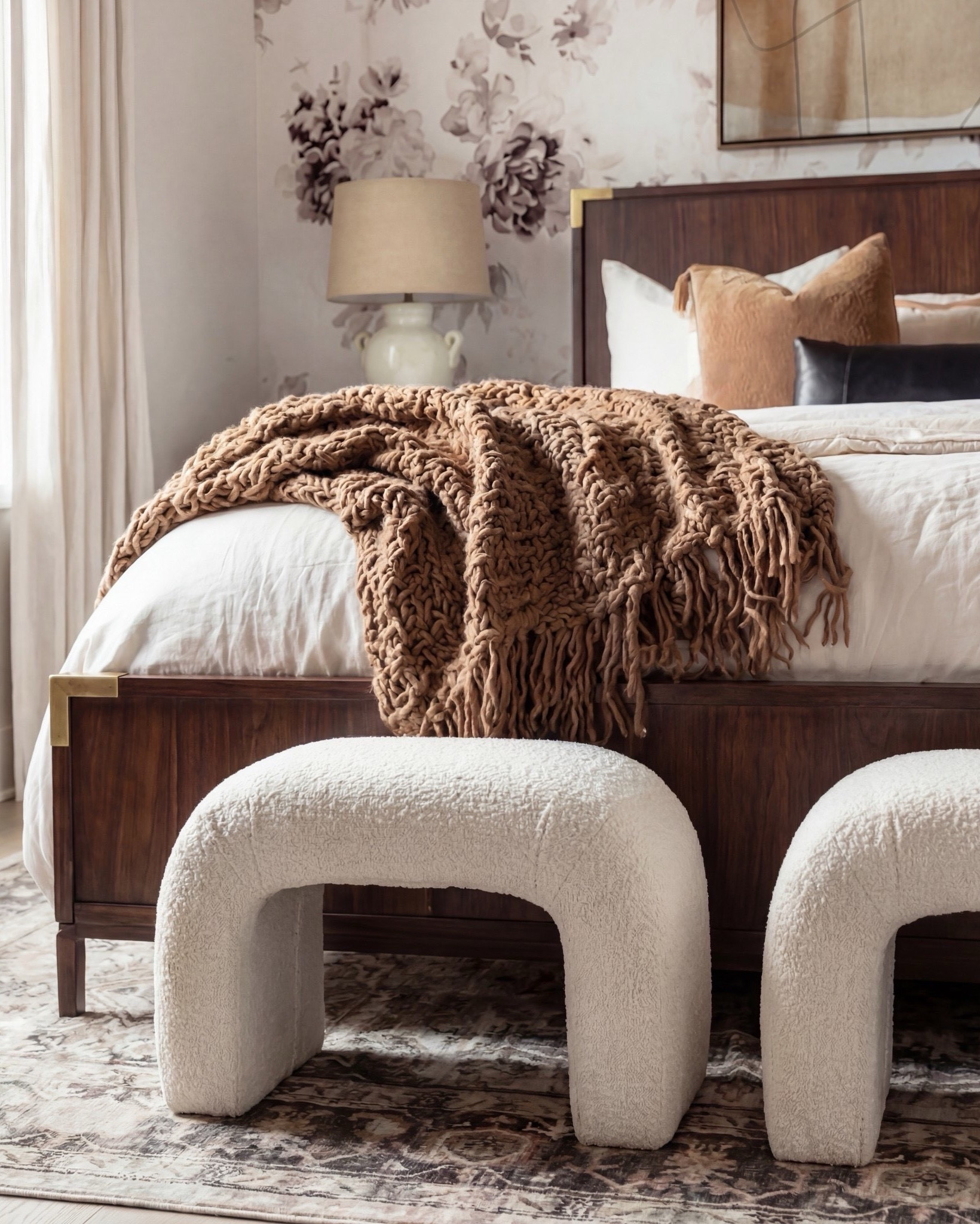 Shop the Look:
• Floral wallpaper (taupe, mauve, soft brown tones)
• Walnut wood bed with brass corner accents
• Cream duvet with layered neutral bedding
• Caramel + rust throw pillows
• Black lumbar pillow (matte leather look)
• Chunky caramel knit throw
• White ceramic bedside lamps
• Walnut 3-drawer nightstands
• Bouclé curved stools
• Neutral vintage-style rug with soft brown pattern
• Abstract wall art (warm neutrals + charcoal

#LTKsale #LTKhome #LTKstyletip