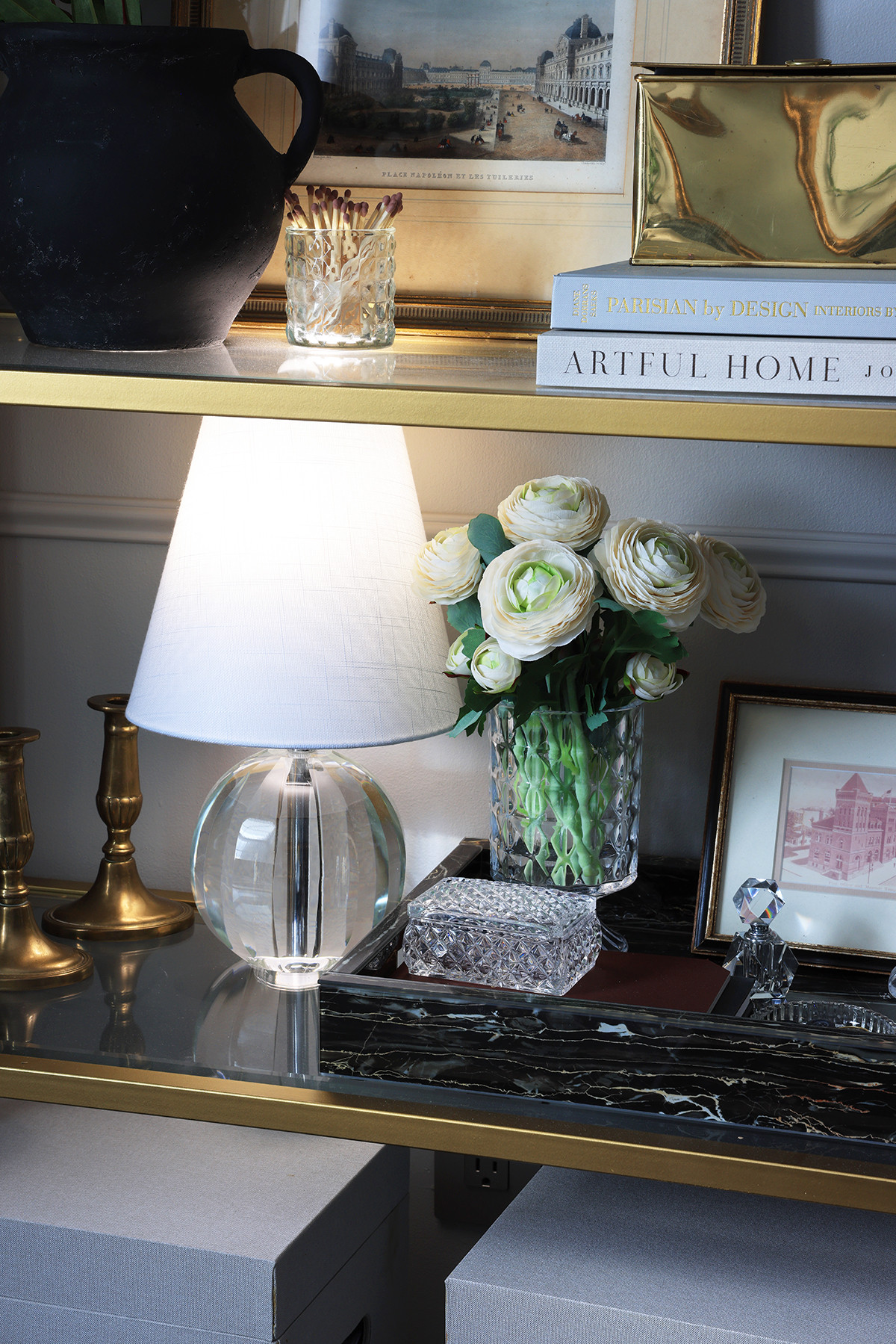 Bookcase styling | Lifelike artificial Rununculous flowers in an embossed glass vase | Small glass lamp | Black marble tray | Decorative coffee table books on home decor | Brass storage box | Matches in glass holder 

 #LTKHome