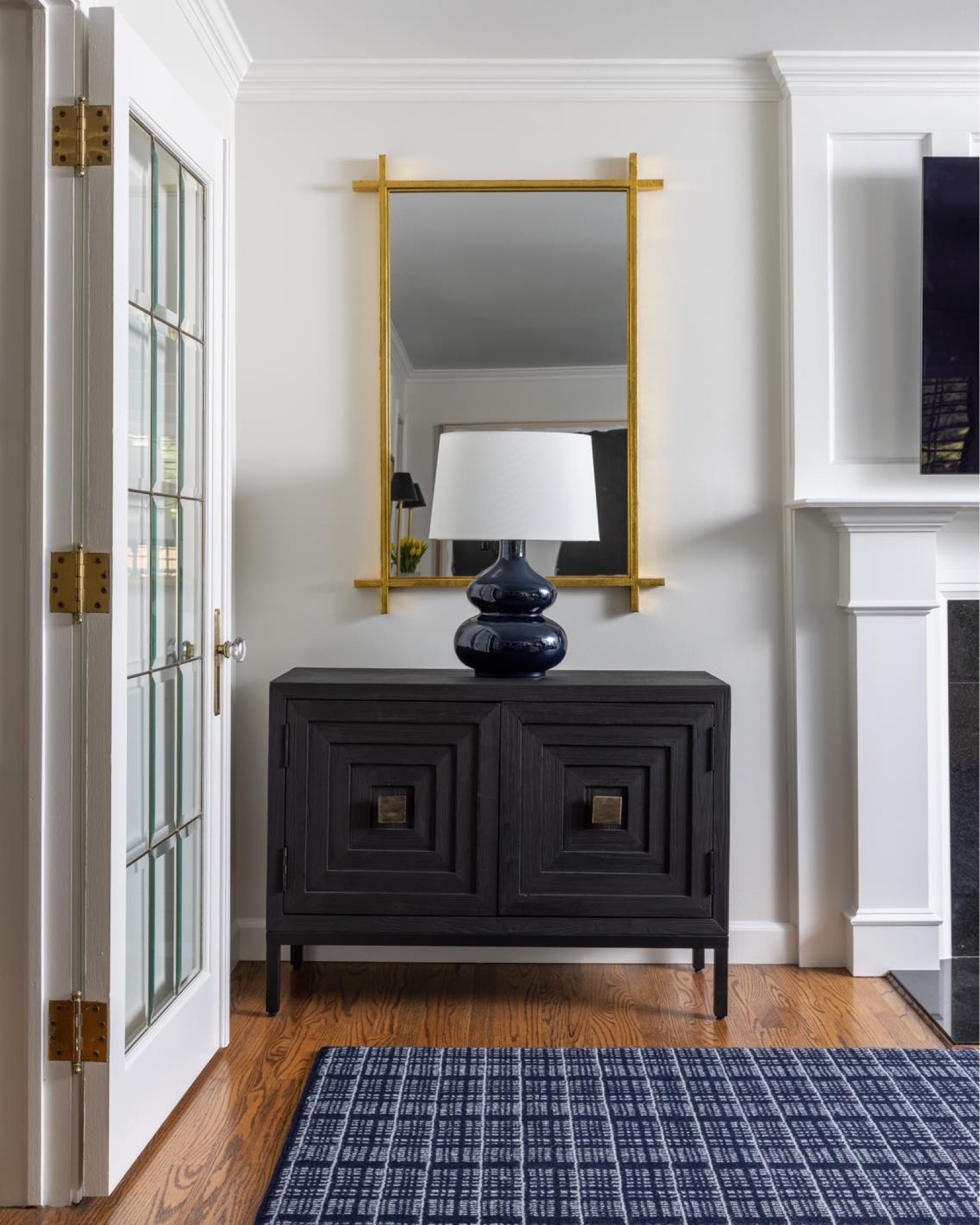 A stylish corner, featuring a bold console with geometric details, a sleek gold-framed mirror, and a glossy navy lamp to compliment the warm, textured rug. Simple and sophisticated!

#interiordesigner #interiordesign #styling #stylingtips #interiordecor #livingroom #livingroomdecor #updatedlivingspace #simplehomestyle #updatedhomedecor #consoletable #mirror #lamp