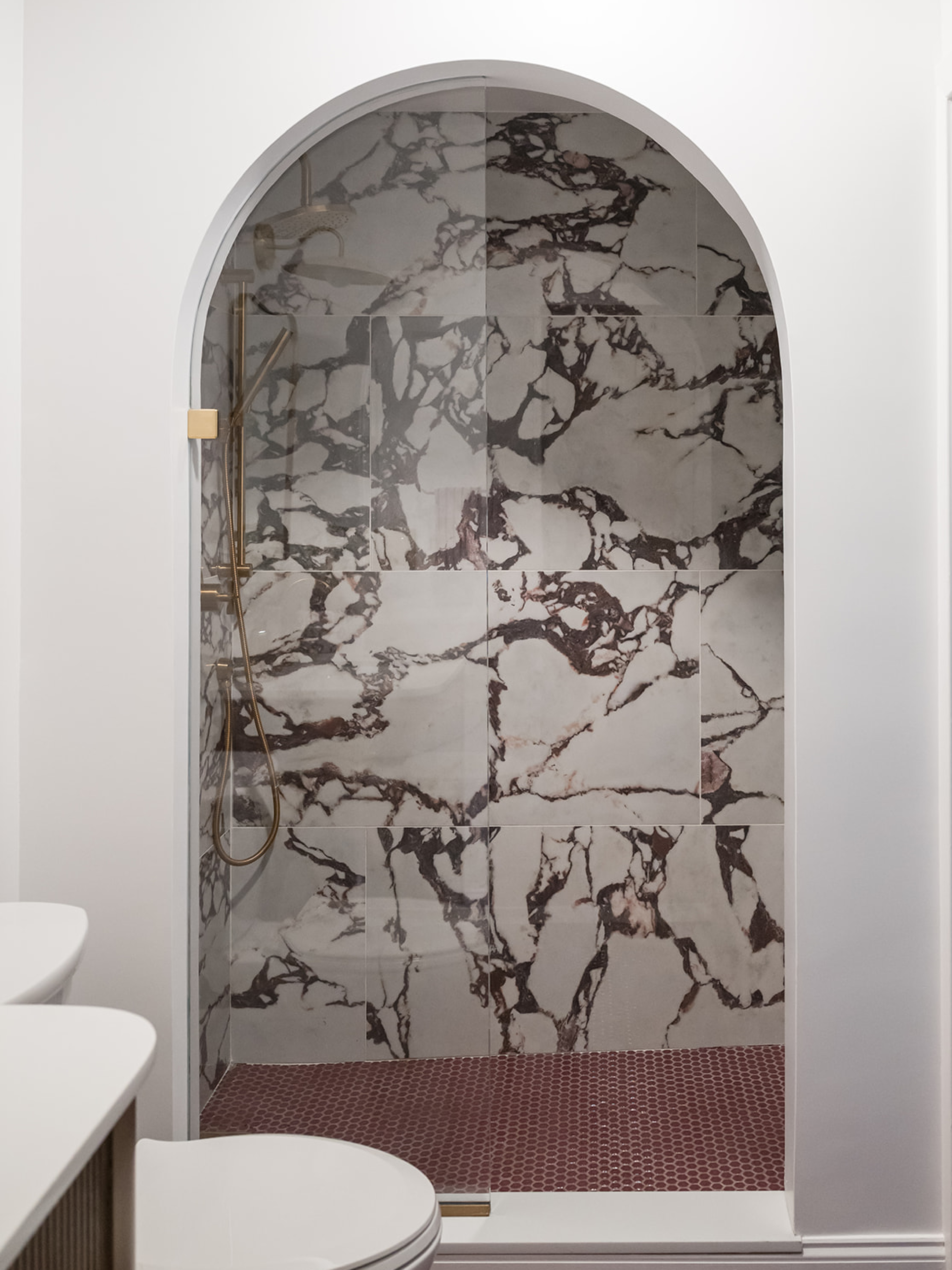 when updating the bathroom at this #dwelloctoberstudio project, we were inspired to convert the tub/shower unit into a walk-in shower with a dramatic arched entry. we selected a bold Calacatta Viola-inspired large format porcelain tile for the shower walls and a deep plum hexagon mosaic tile for the floor. brushed gold plumbing fixtures and a fixed panel of curved glass add the finishing touches to this luxurious shower. #dwelloctober

#LTKHome