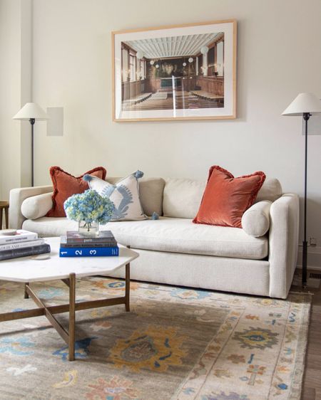 Classic living room style with pops of color, orange pillows, modern artwork, marble coffee table, small space sofa, classic style, traditional rug, Oushak rug 

#LTKhome #LTKstyletip